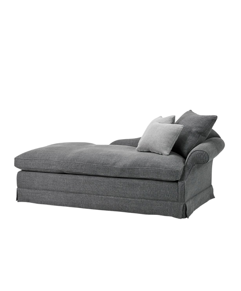 A gray upholstered chaise longue with soft, rounded edges and two pillows. The chaise longue has a relaxed, comfortable look with a slightly flared backrest.