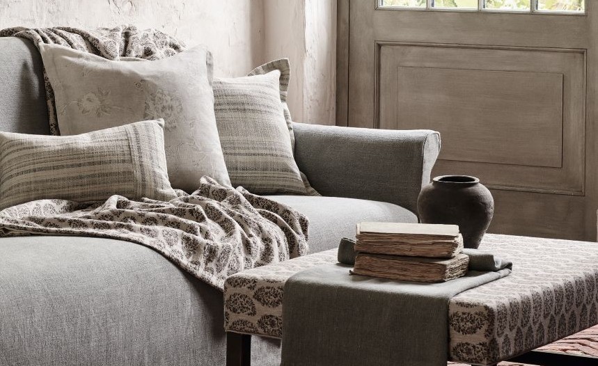 Cozy grey Matomba sofa by Collett & Victor styled with patterned cushions, soft throw blanket, and rustic coffee table with vintage books and ceramic vase.
