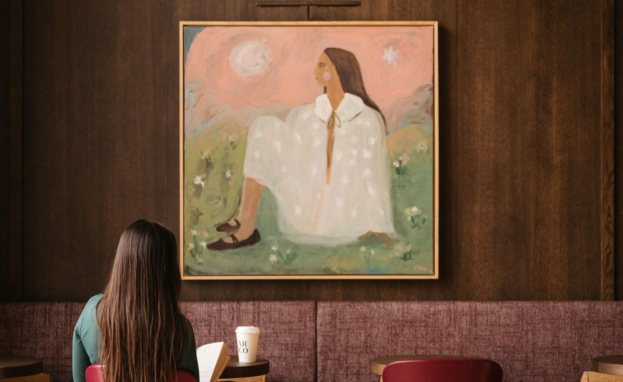 Woman sat, reading a book with a coffee on the table at Dear Coco