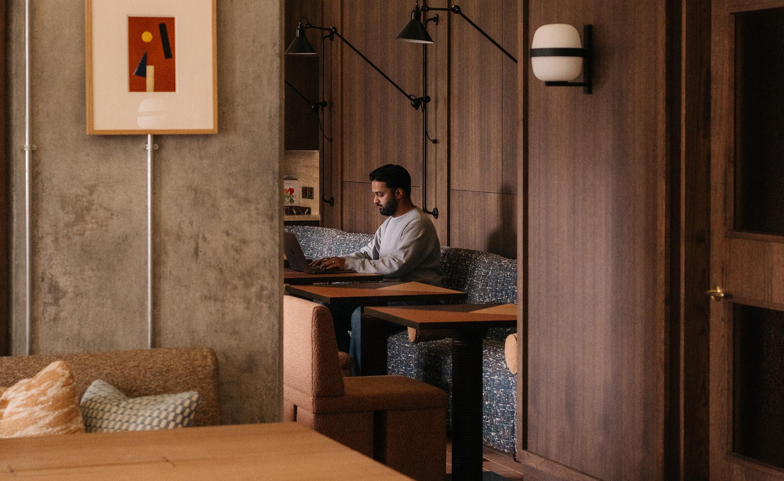 Man working on laptop in co-working space booth at The Draper luxury apartments to rent. [G]