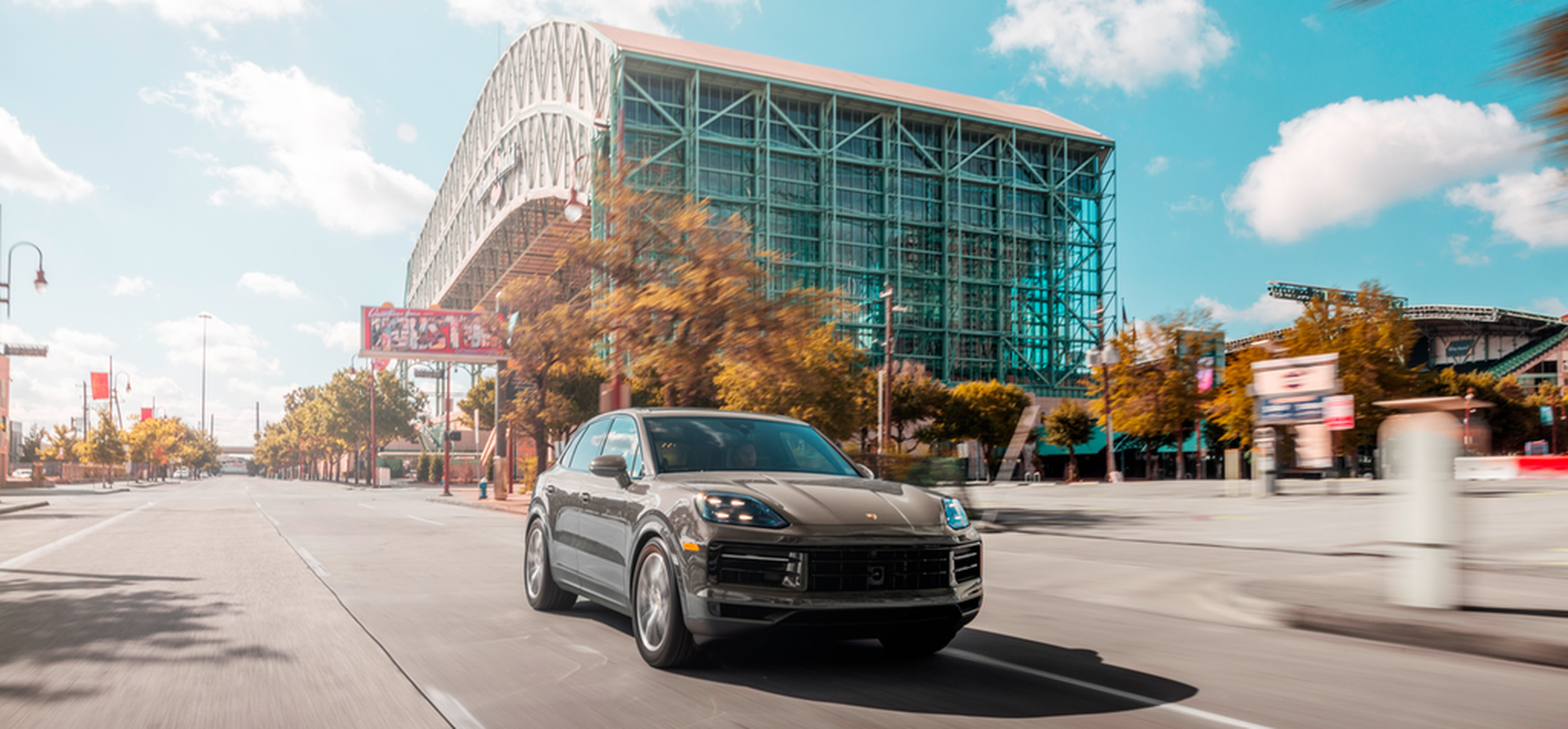 Gray Porsche Cayenne in front of a glass building