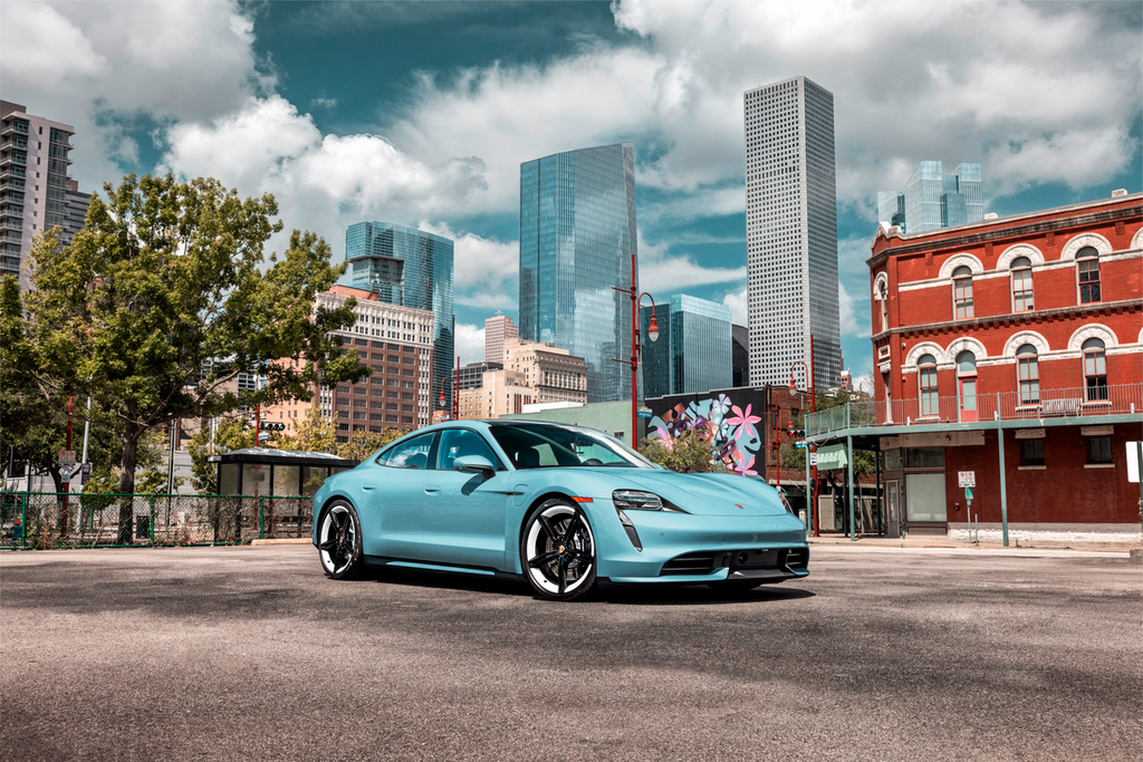 Teal Porsche Taycan parked downtown in front of skyscrapers