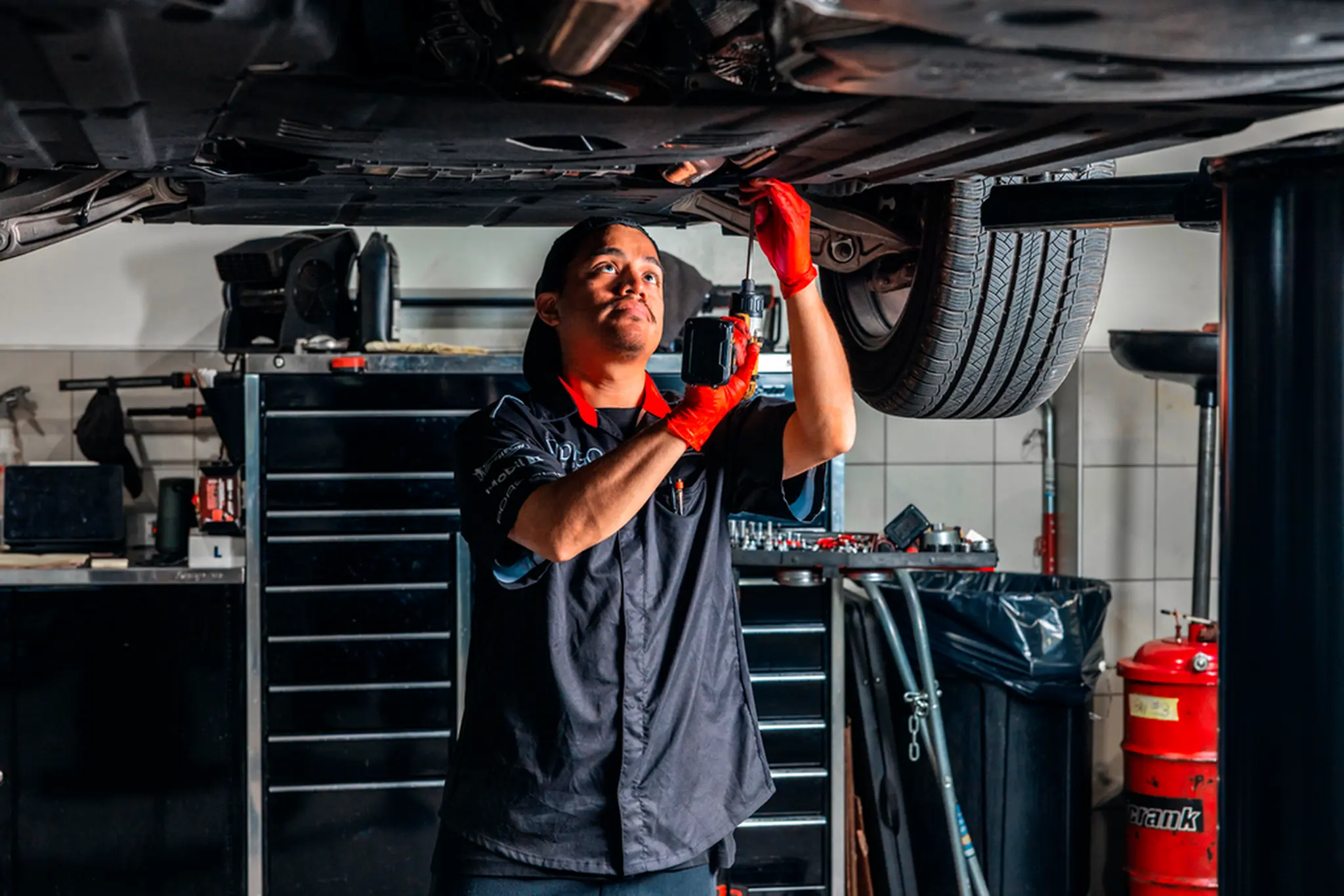 Porsche technician inspecting the underside of a car on a lift