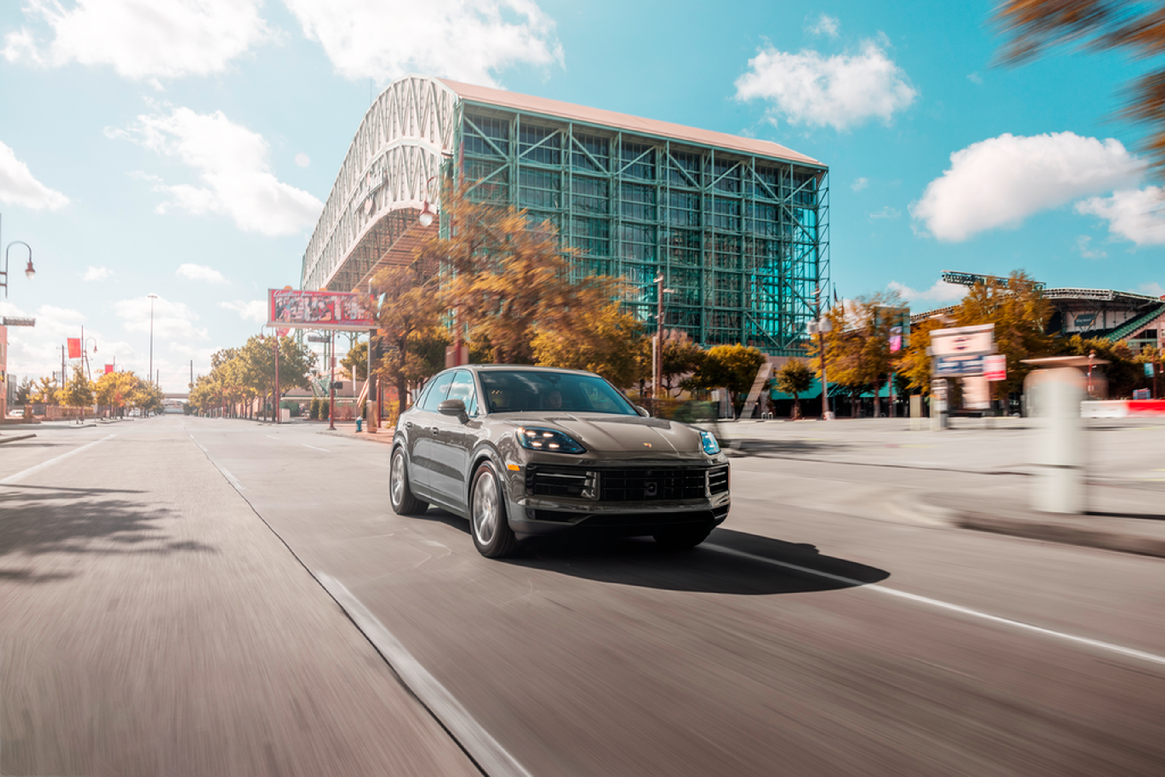 Gray Porsche Cayenne by a glass tower
