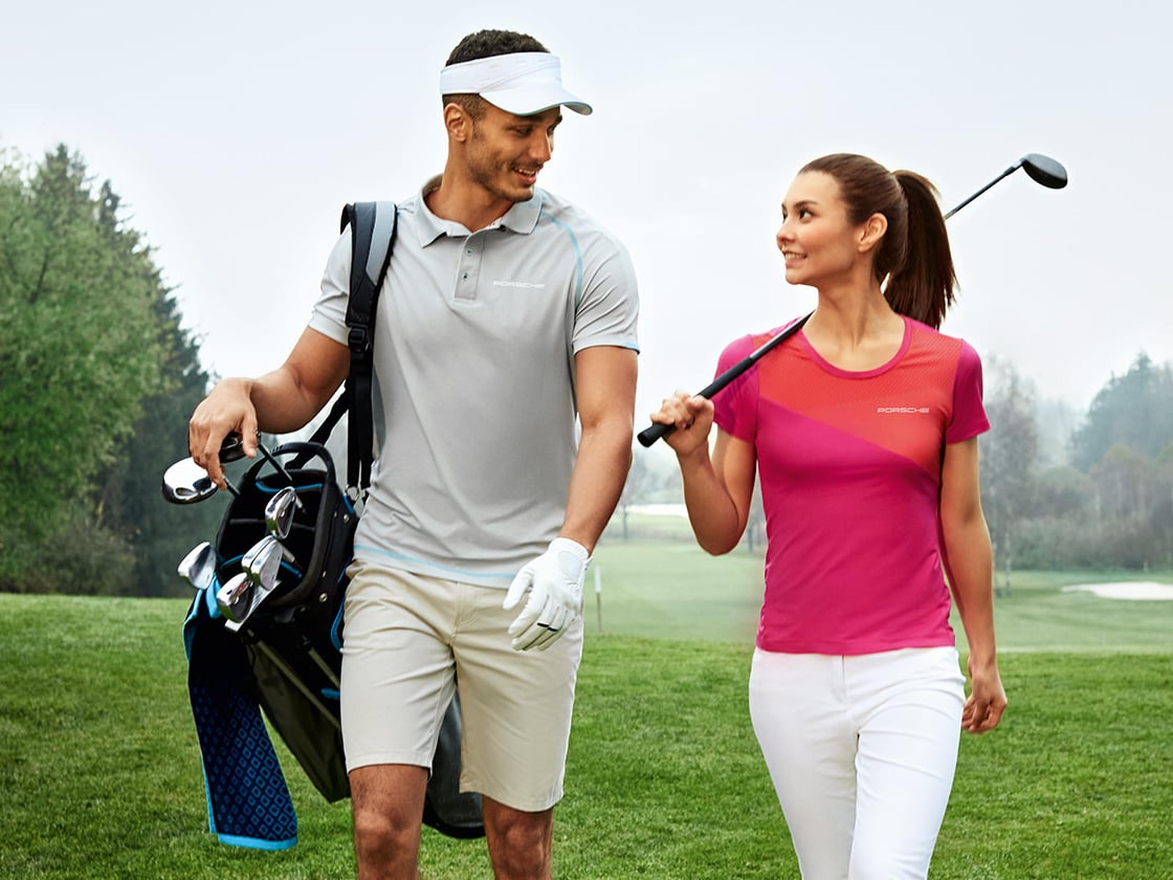 Zwei Personen in Porsche Golfbekleidung auf dem Rasen.