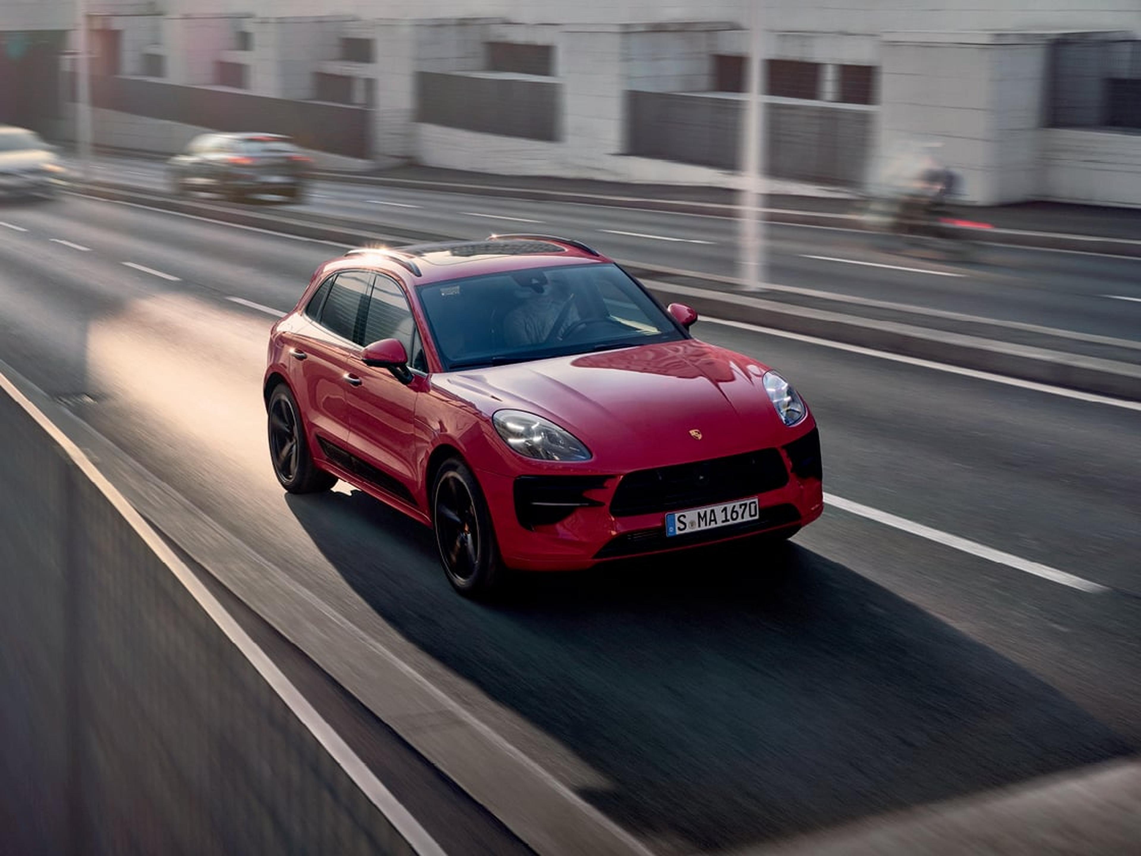 Porsche Macan rojo conduciendo en una autopista, mostrando su diseño deportivo y rendimiento en movimiento.