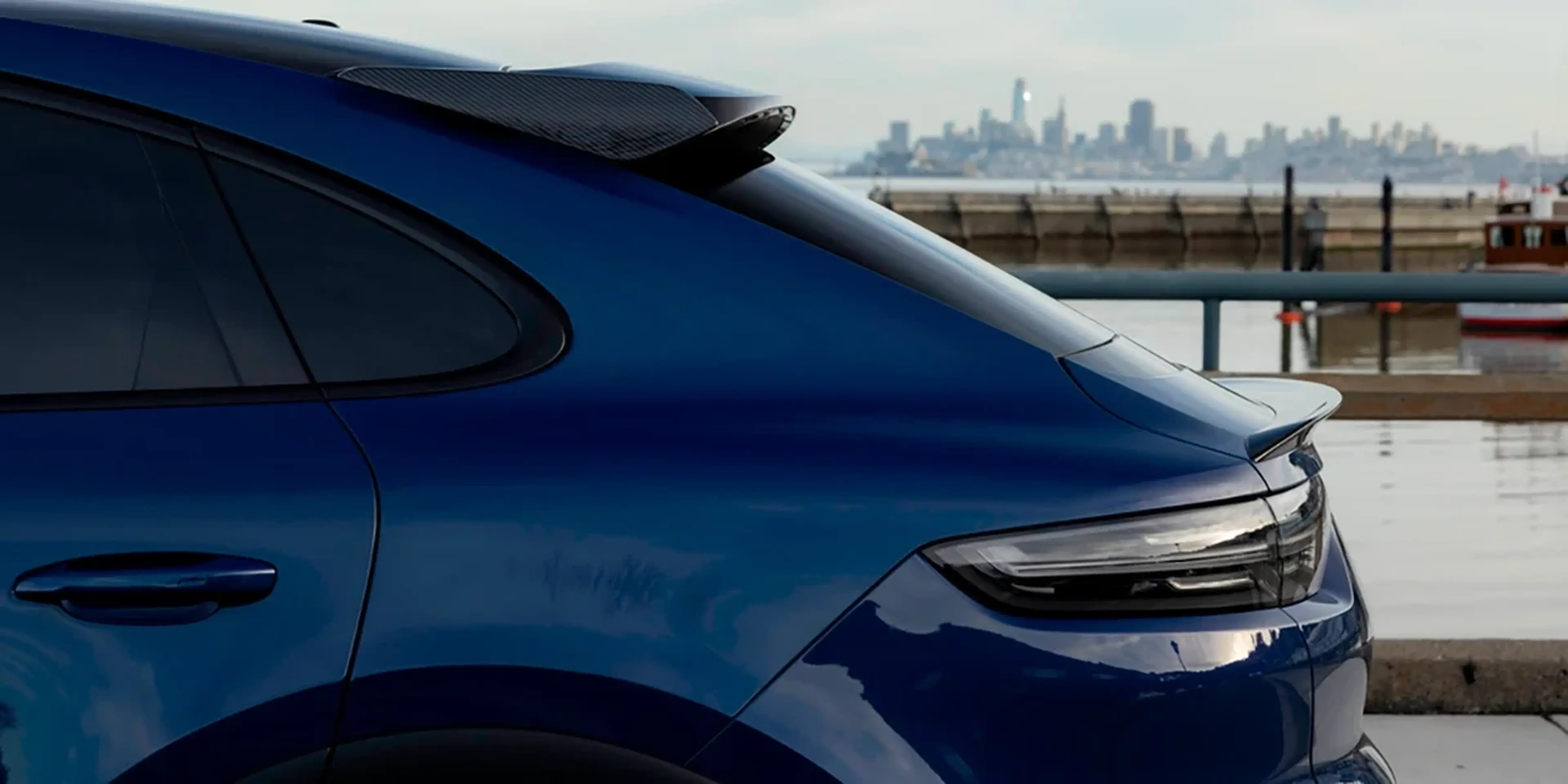 Rear of a blue Porsche Cayenne with the San Francisco skyline in the background
