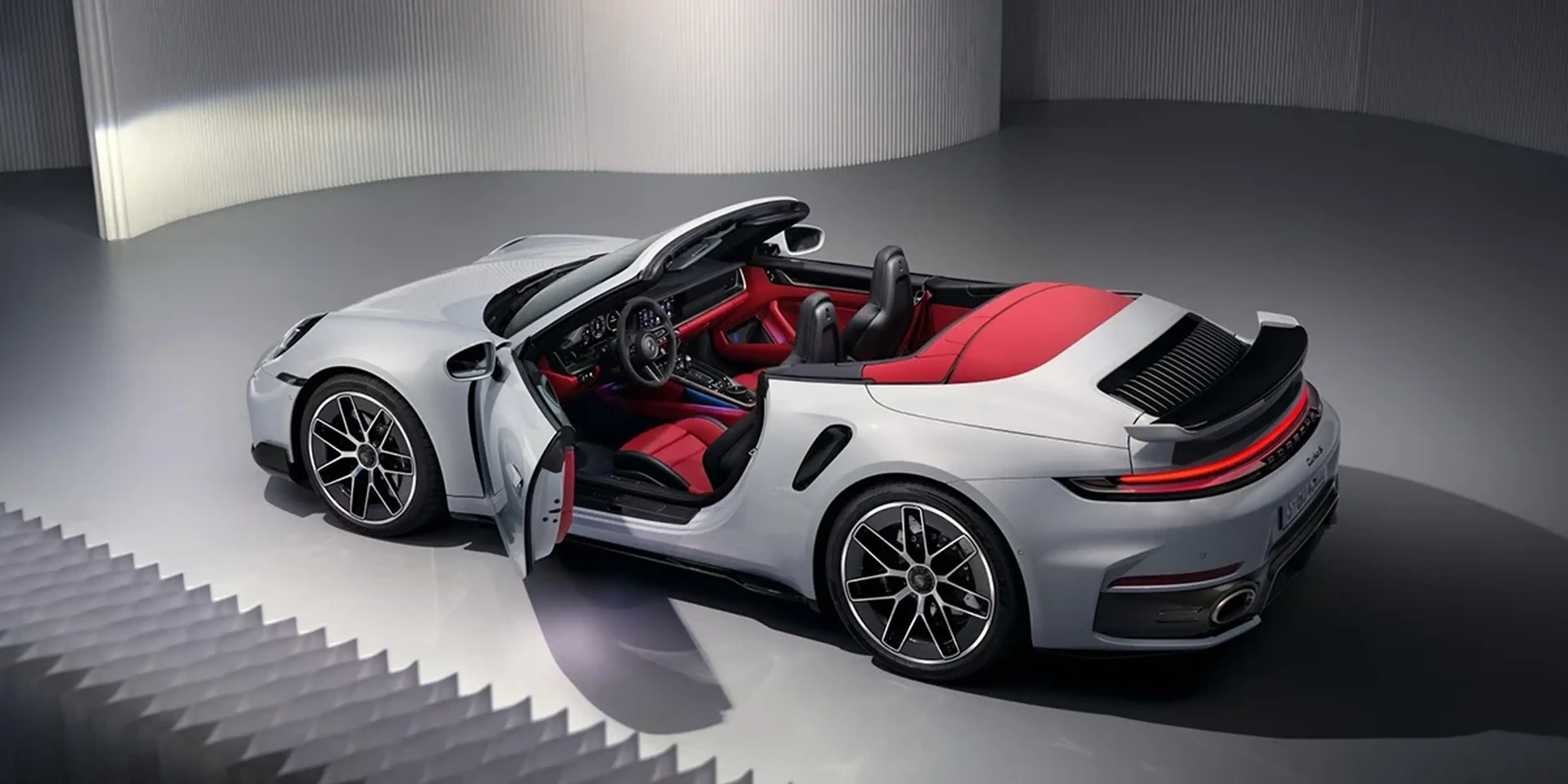 Porsche 911 Turbo S Cabriolet studio shot, angled front view highlighting headlights and bumper design.