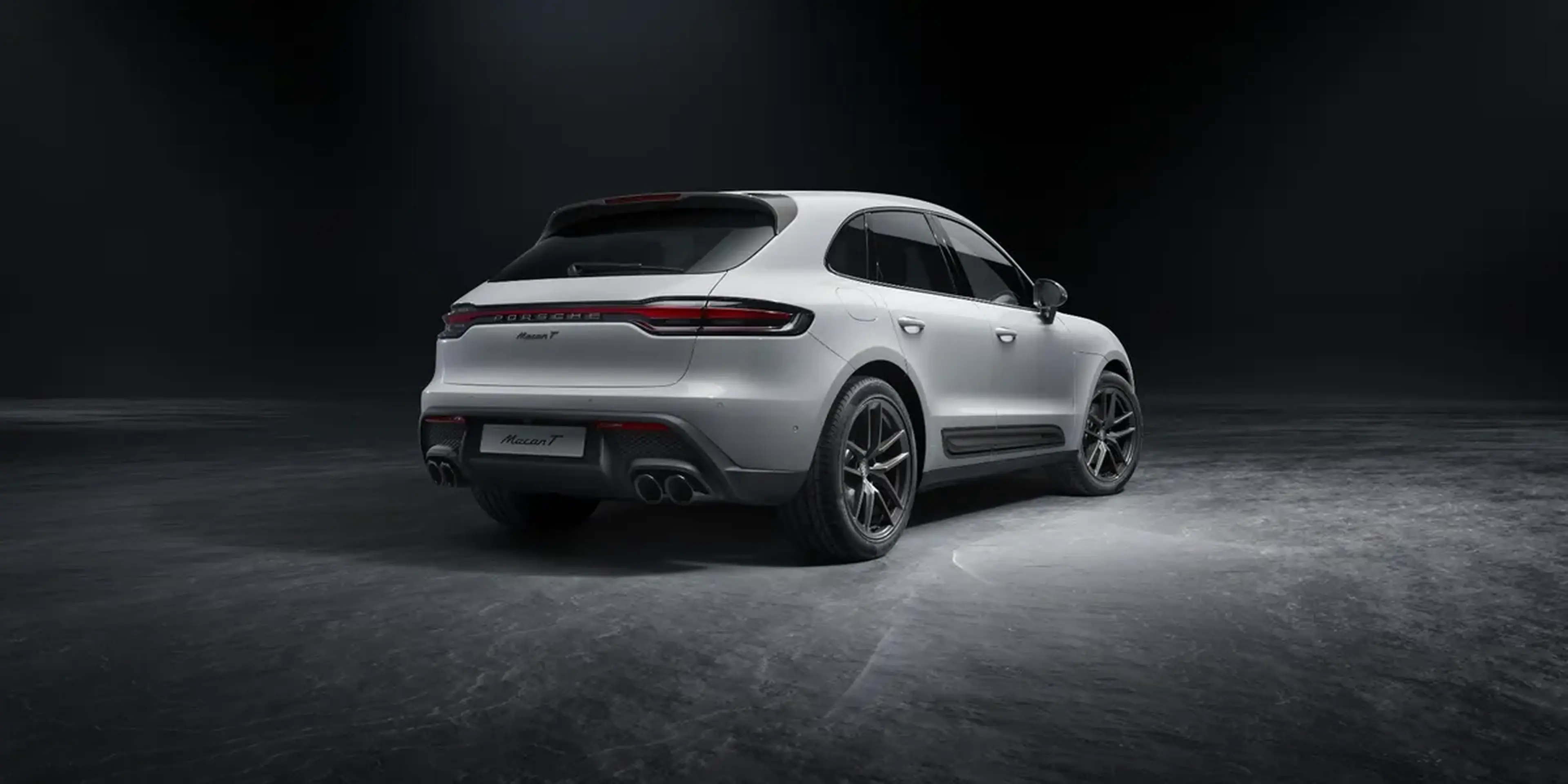 Three-quarter rear view of Porsche Macan T in a dark studio environment