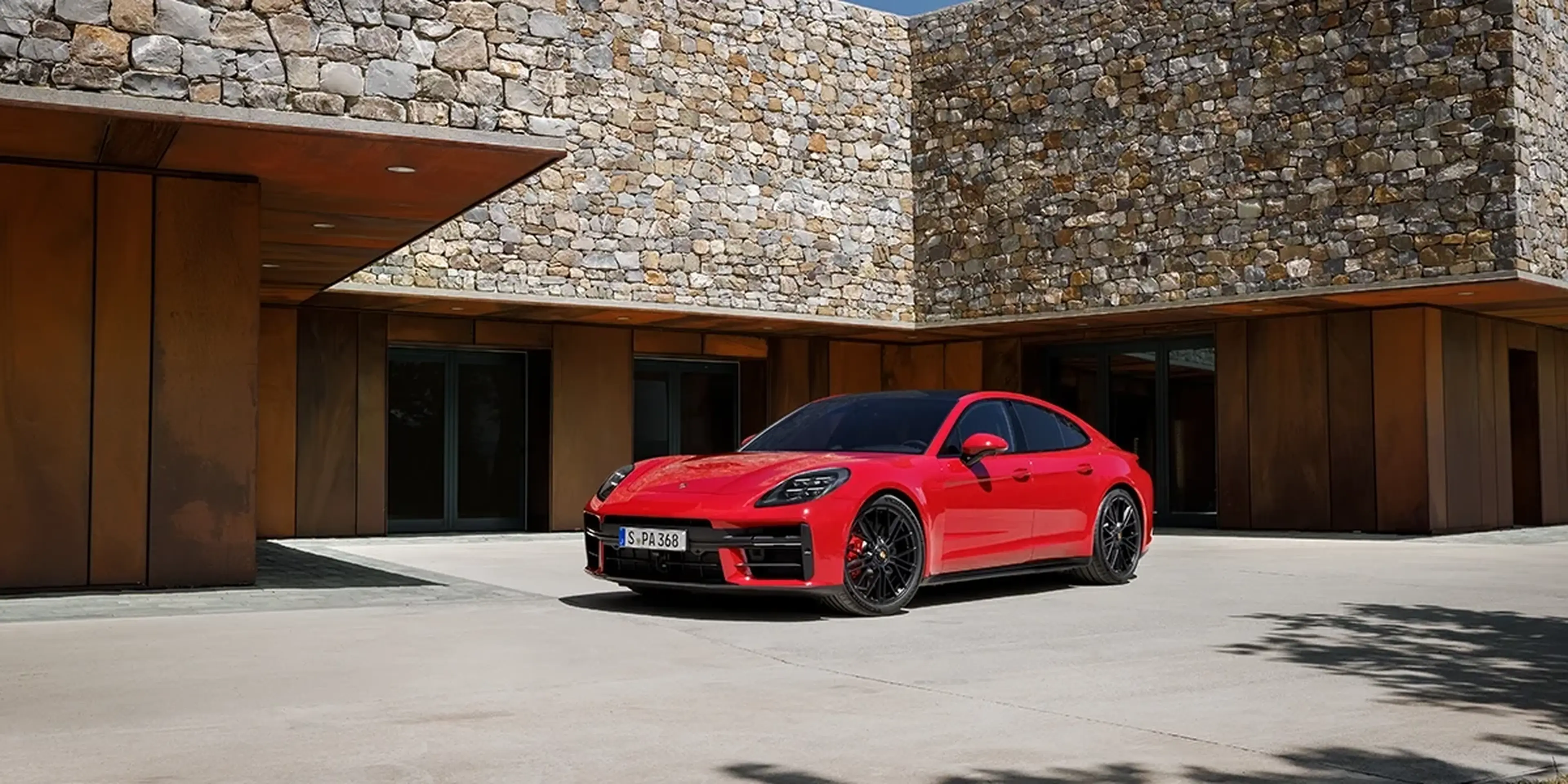Red 2025 Porsche Panamera GTS parked by a stone building