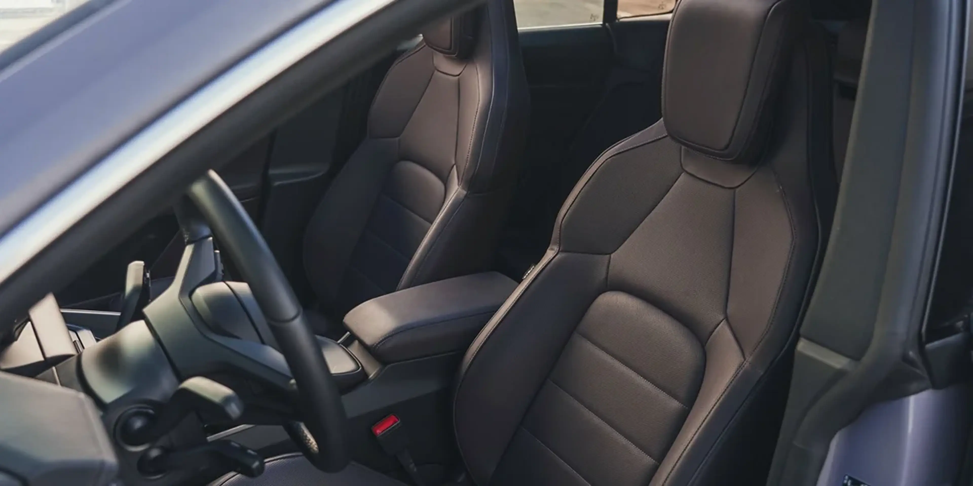 Front seats of the 2024 Porsche Macan 4S in black leather upholstery with premium stitching.