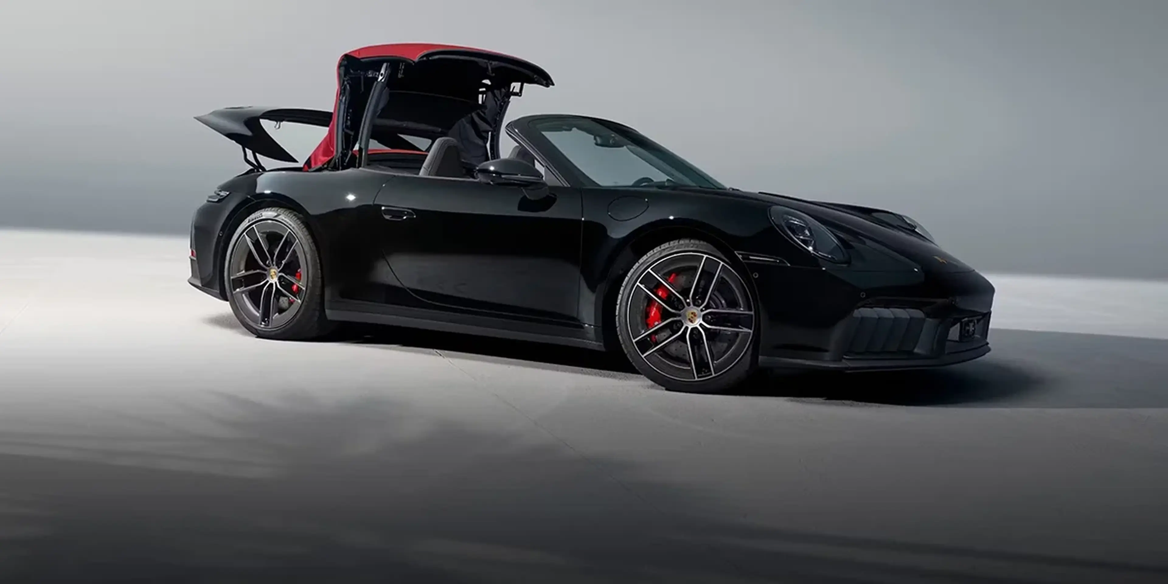 2026 Porsche 911 Carrera 4S Cabriolet driving along the Pacific Coast Highway with top down, illustrating open-air performance and refined driving experience.