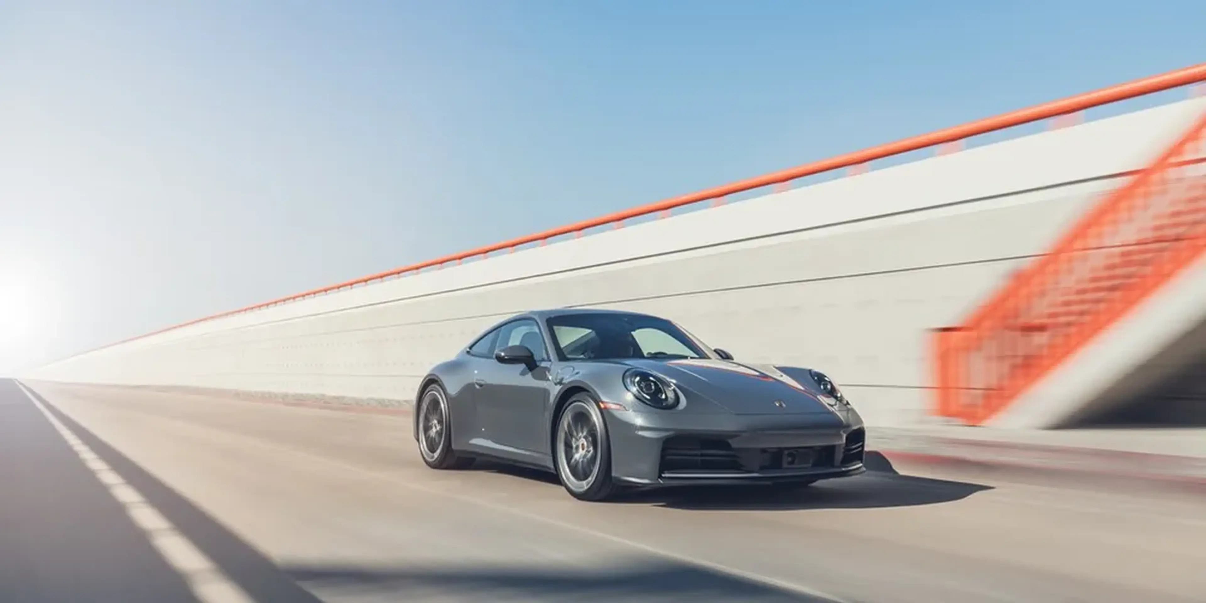 2026 Porsche 911 Carrera front three-quarter view in motion on elevated roadway