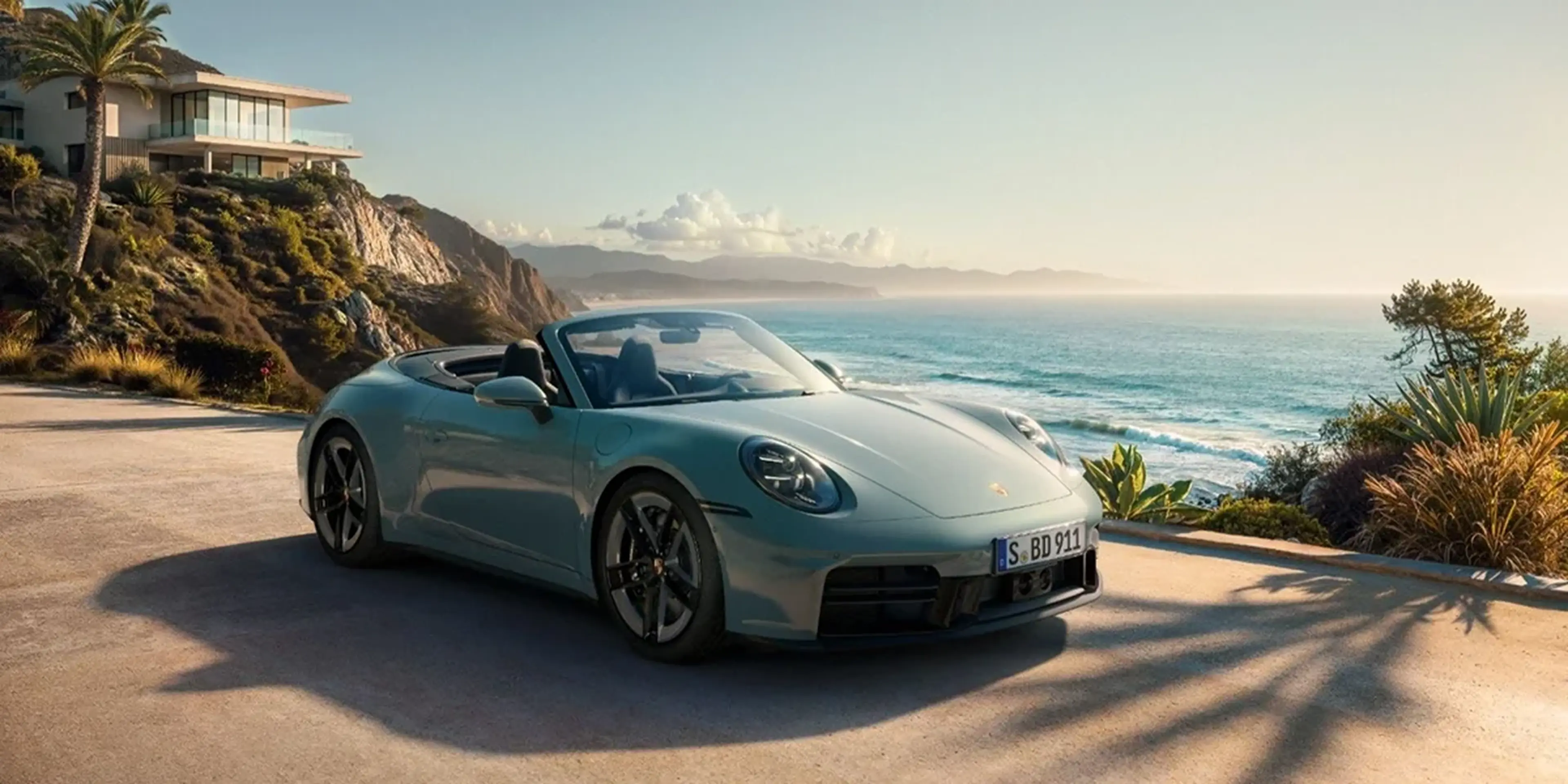 Rear angle of 2026 Porsche 911 Carrera 4S Cabriolet cruising along the California coastline, emphasizing the convertible design and scenic performance lifestyle.