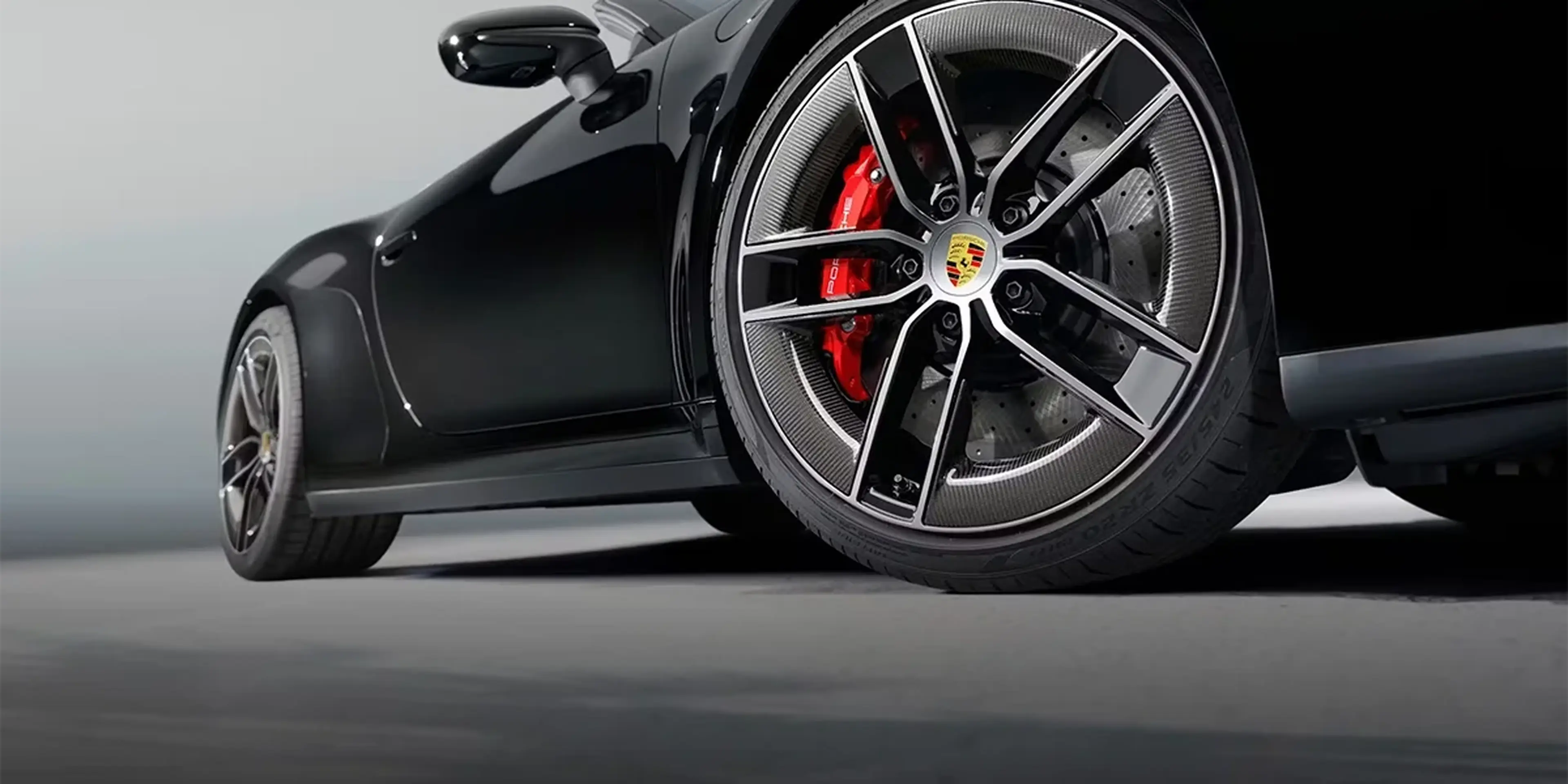 Close-up of 2026 Porsche 911 Carrera 4S Cabriolet carbon wheel and red brake calipers, representing all-wheel-drive traction and precise handling.