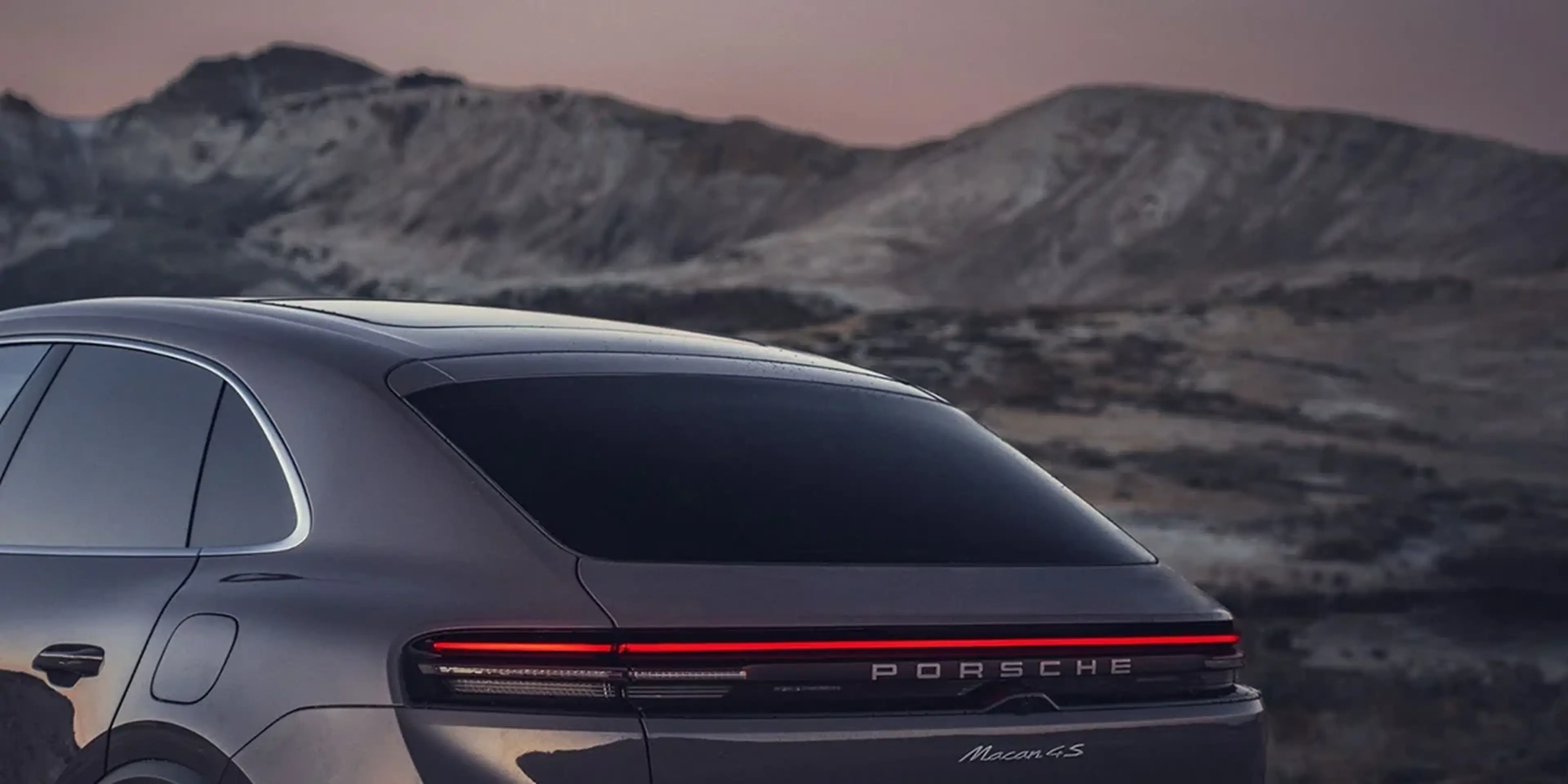 Porsche Macan 4S driving along a mountain road, demonstrating dynamic performance and agility.