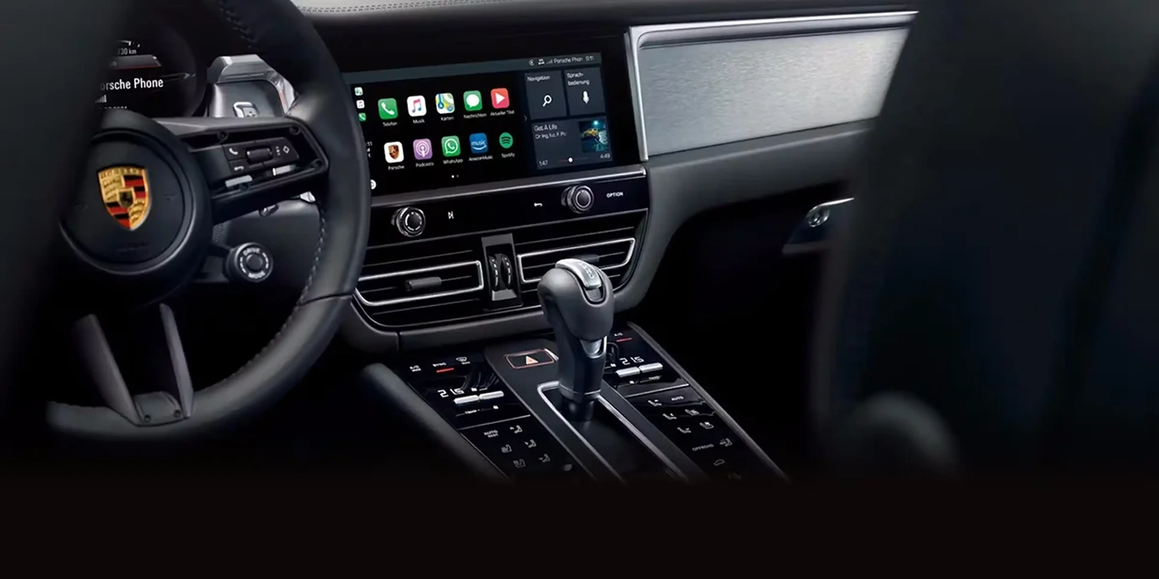 Driver-focused Porsche Macan GTS interior with leather steering wheel, touchscreen infotainment, and sport-inspired center console.