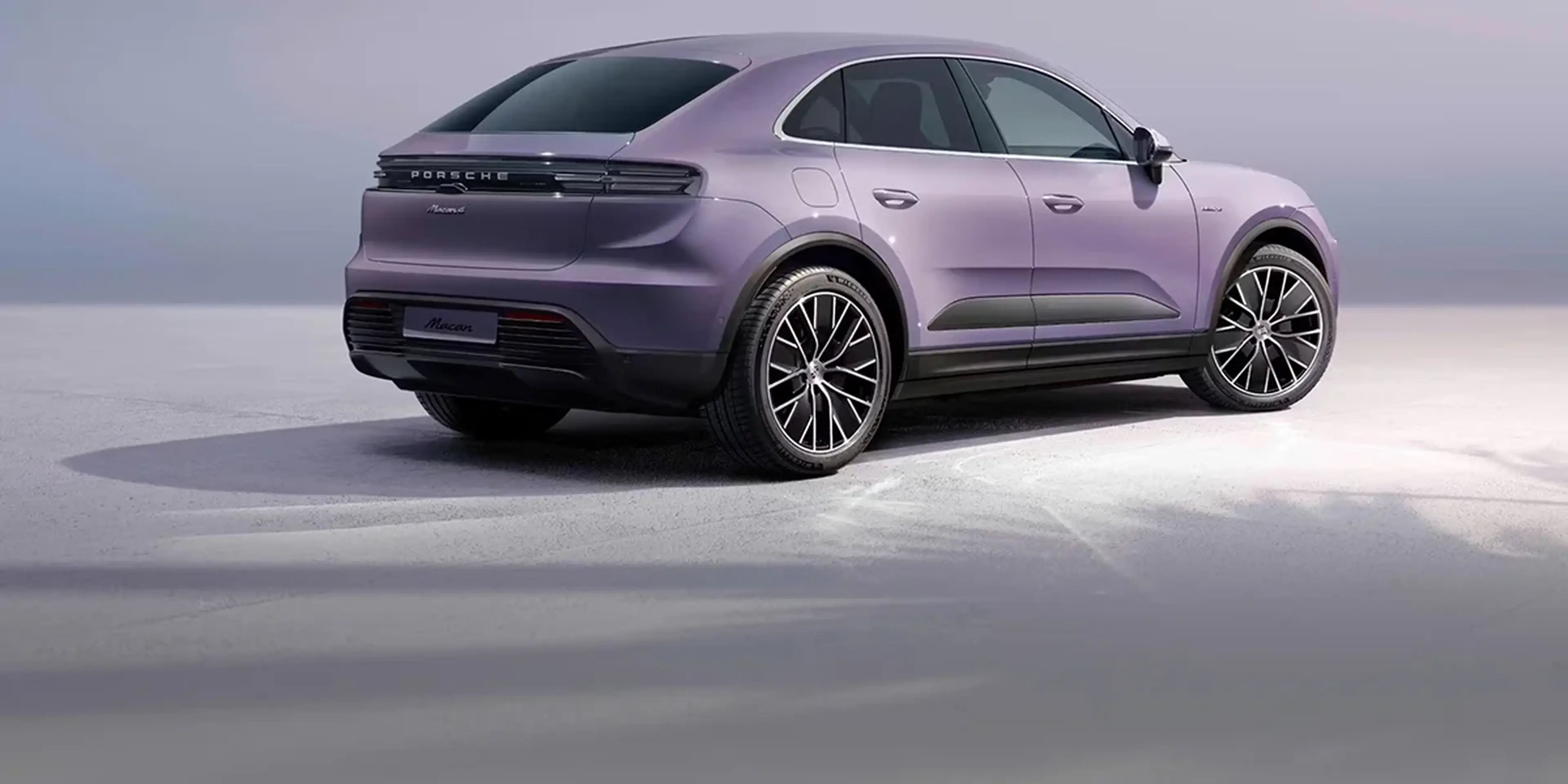 Front view of blue Porsche Macan T with mountains at sunrise in the background