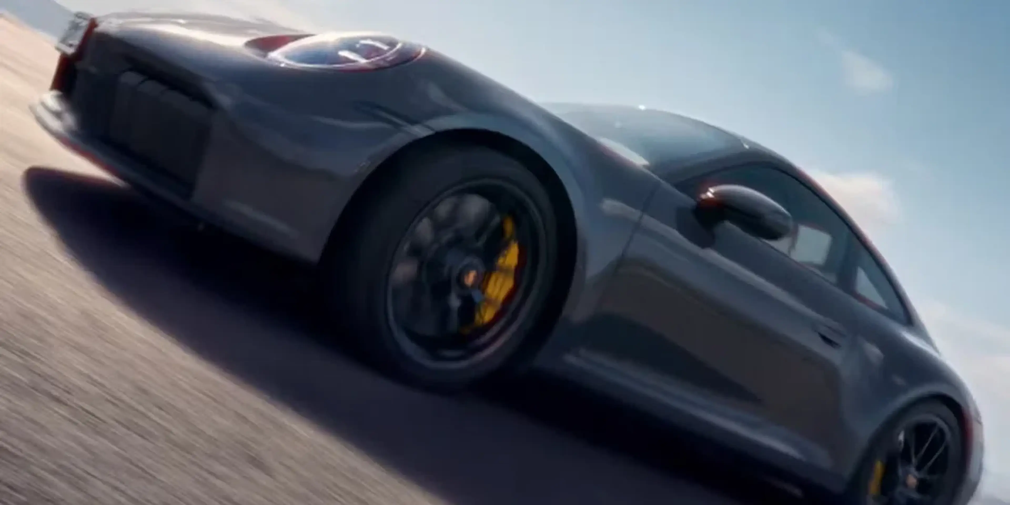 Porsche 911 Carrera 4S in motion, highlighting aerodynamic design and performance stance on open road.