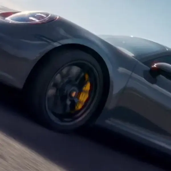 Porsche 911 Carrera 4S in motion, highlighting aerodynamic design and performance stance on open road.