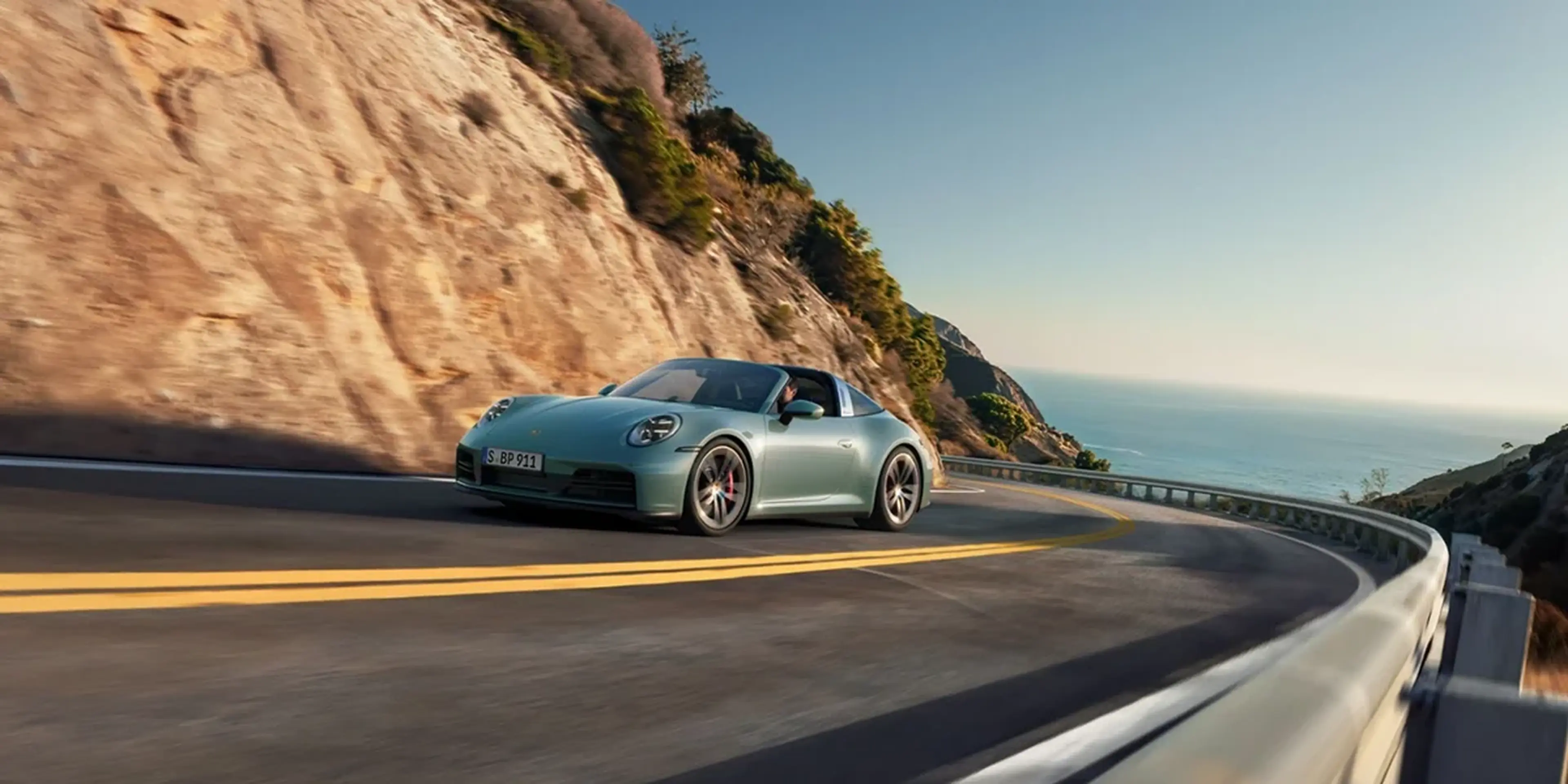 2026 Porsche 911 Carrera 4S Cabriolet in black with red soft top, showcased with the roof mechanism in motion for open-air driving.