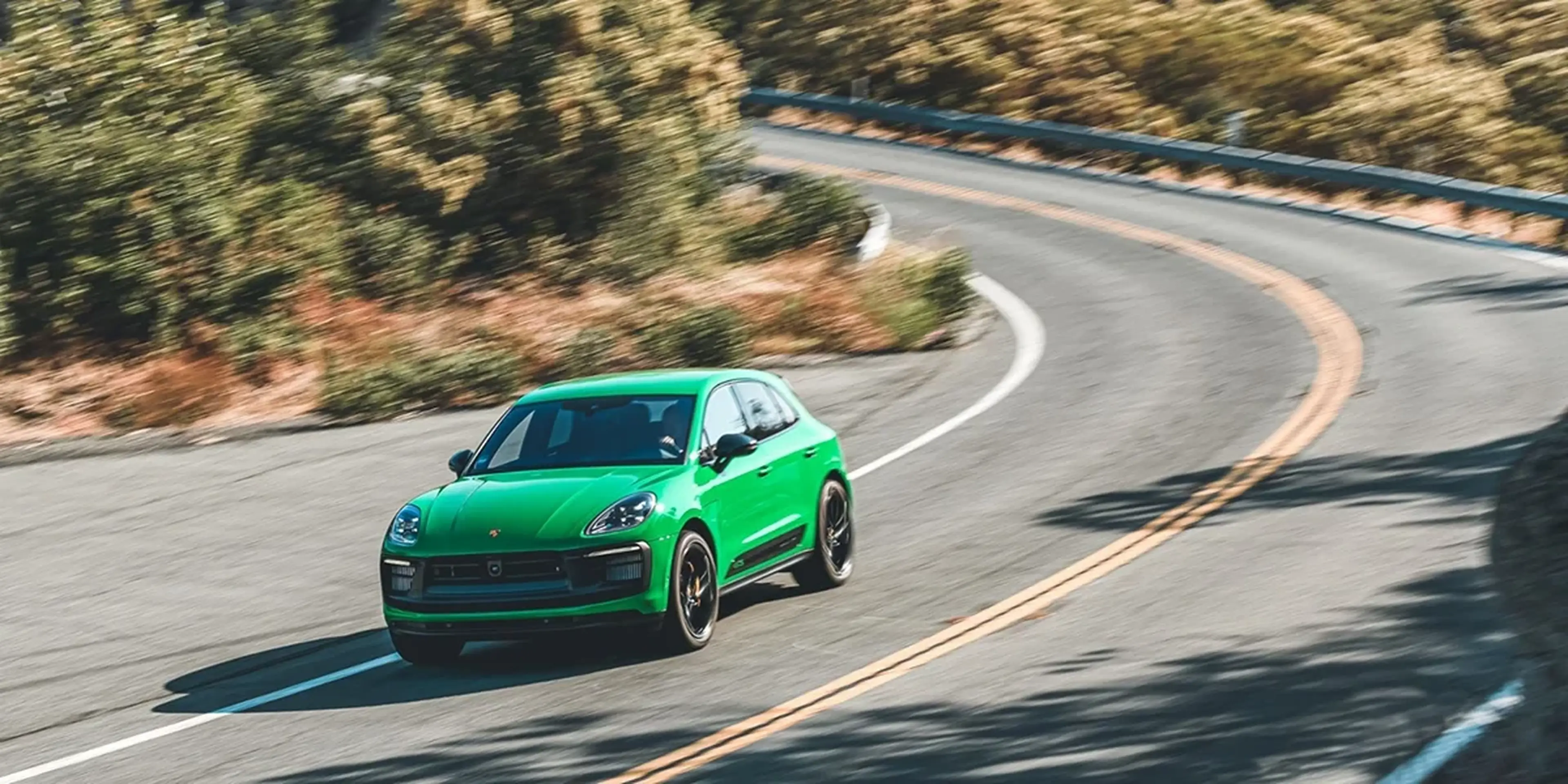 Python Green Porsche Macan GTS carving through mountain roads, underlining precise cornering and agile performance.