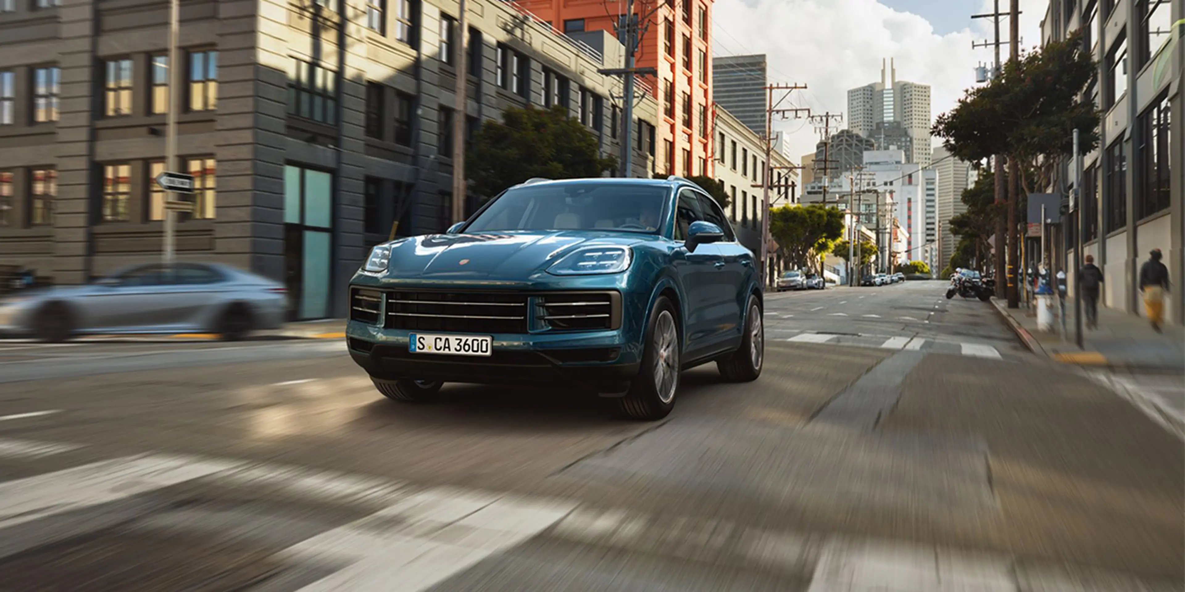 Blue 2025 Porsche Cayenne by brick buildings