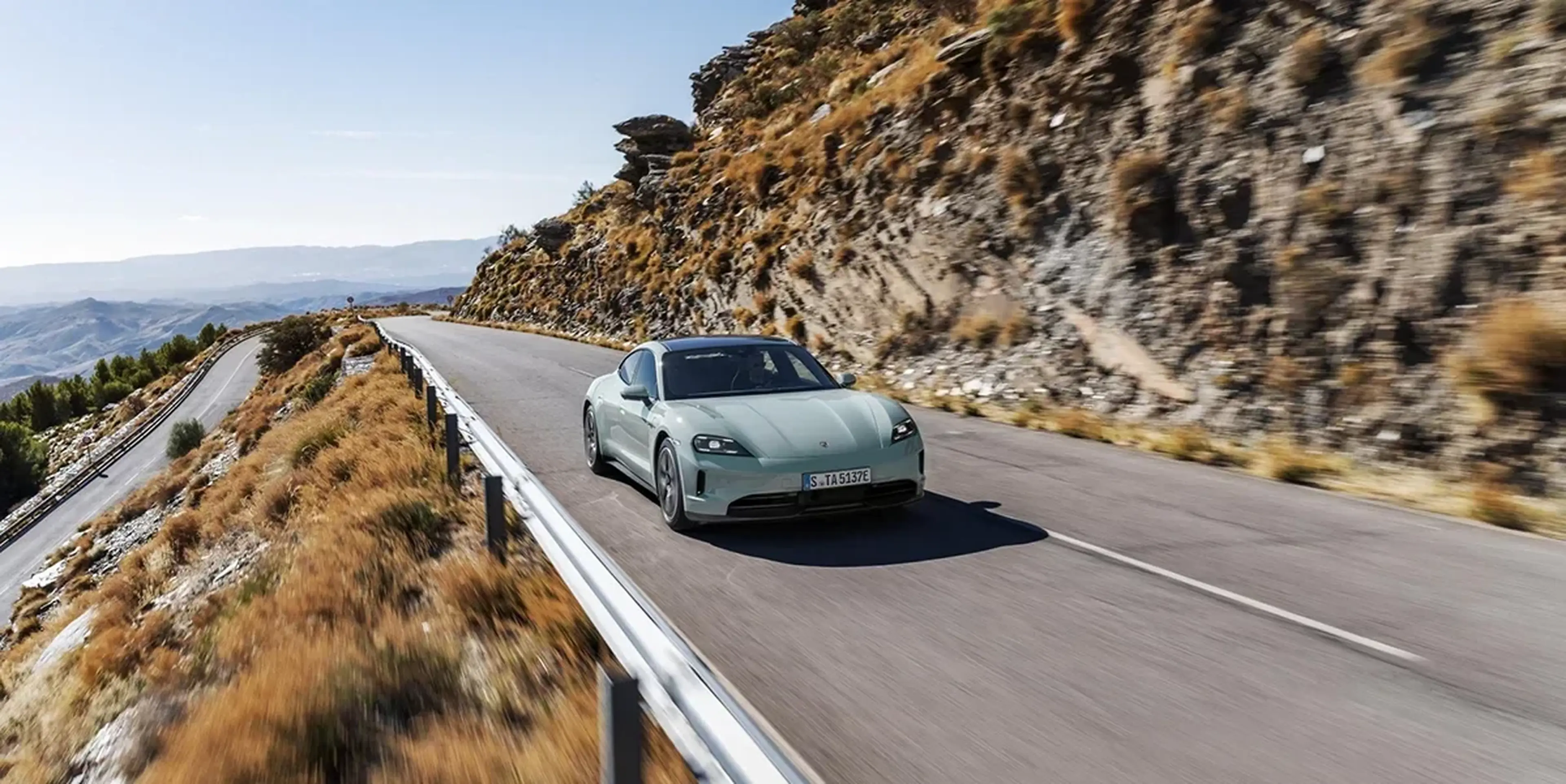 Mint green 2025 Porsche Taycan on a coastal mountain road