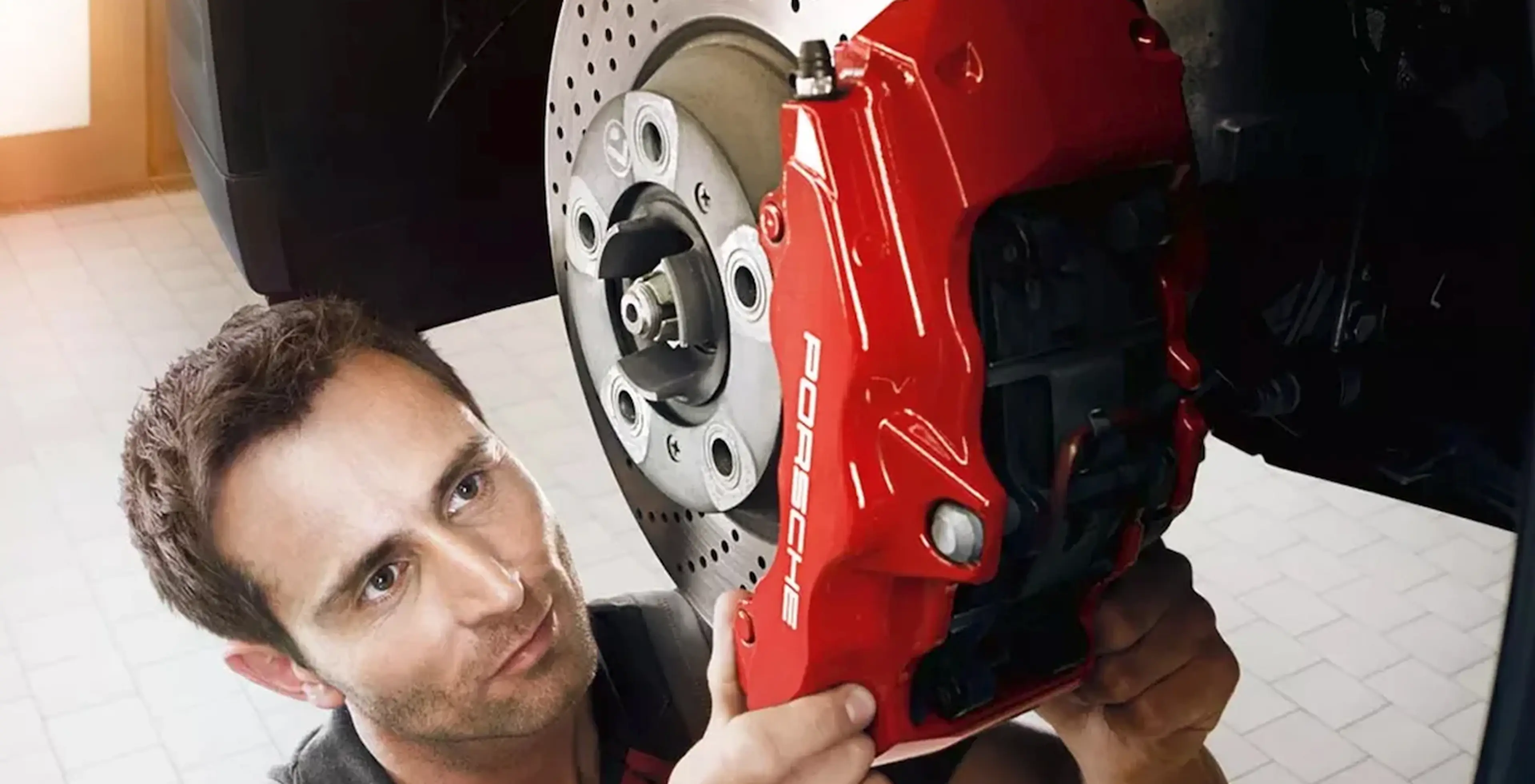 Technician servicing a red Porsche brake caliper