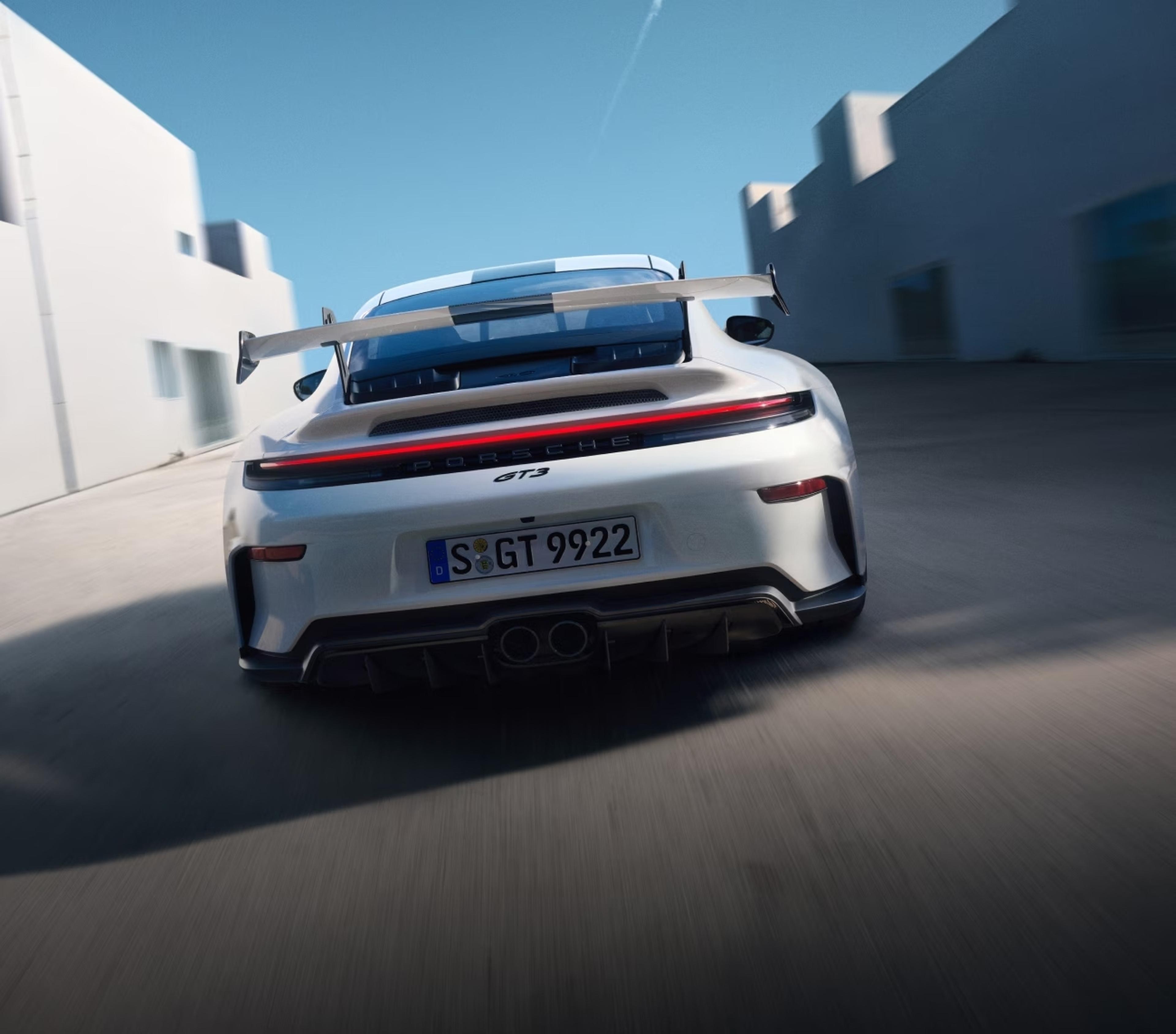 Rear view of the 2027 Porsche 911 GT3 S/C driving between modern buildings