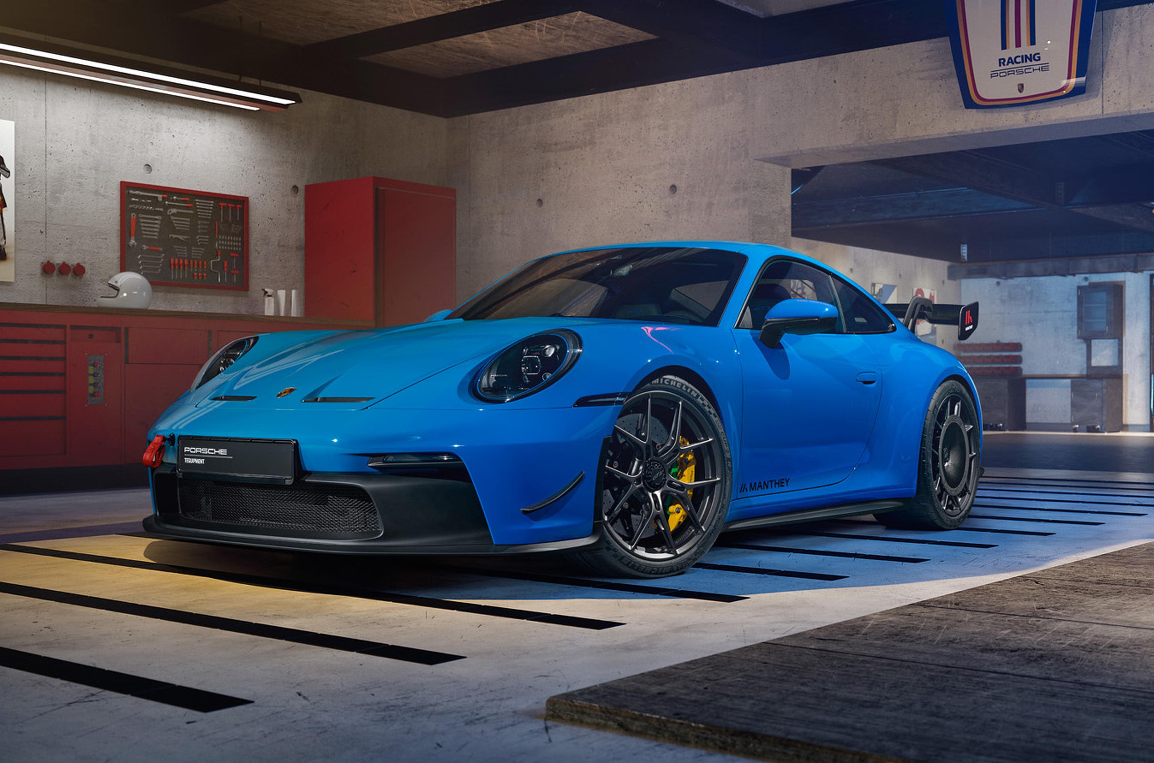 Blue Porsche 911 equipped with Manthey performance components displayed inside a workshop, featuring aerodynamic enhancements and track-focused upgrades.