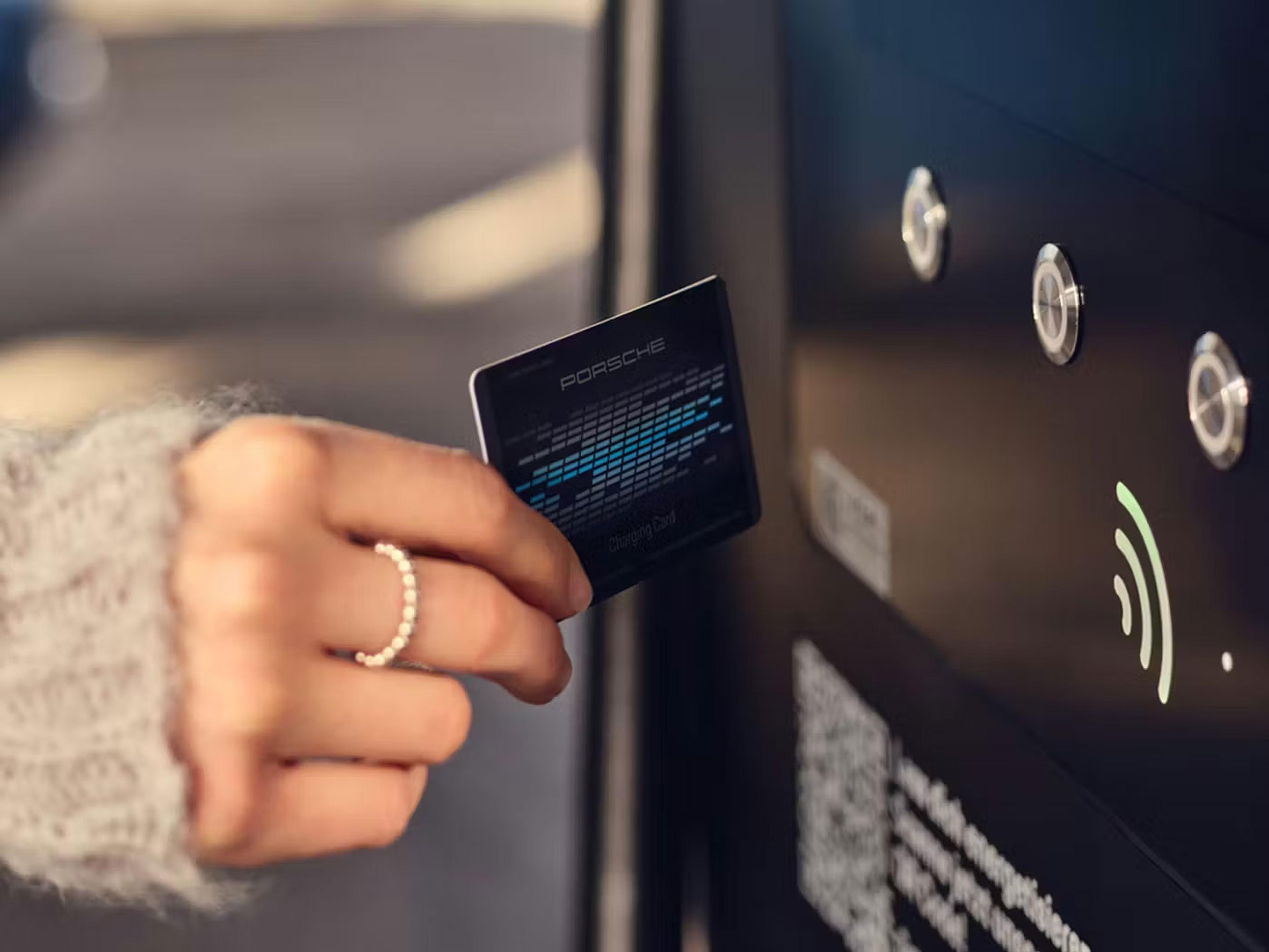 Eine Person in einem Pullover hält eine Karte in die Nähe eines Zahlungsterminals mit NFC-Symbol und bereitet sich auf eine kontaktlose Zahlung vor.