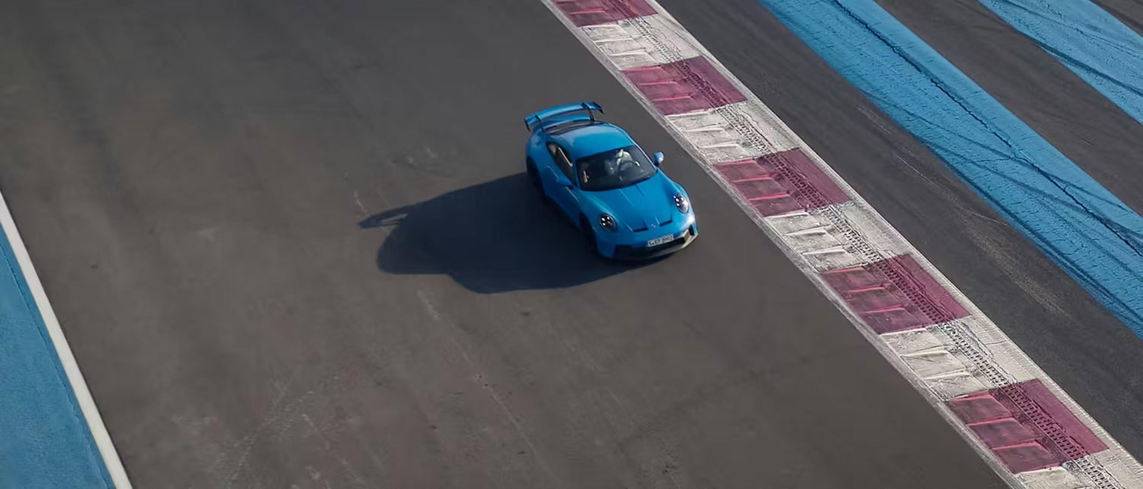 Ein blauer Sportwagen fährt auf einer Rennstrecke mit rot-weiß gestreiften Randsteinen und blauen Markierungen.