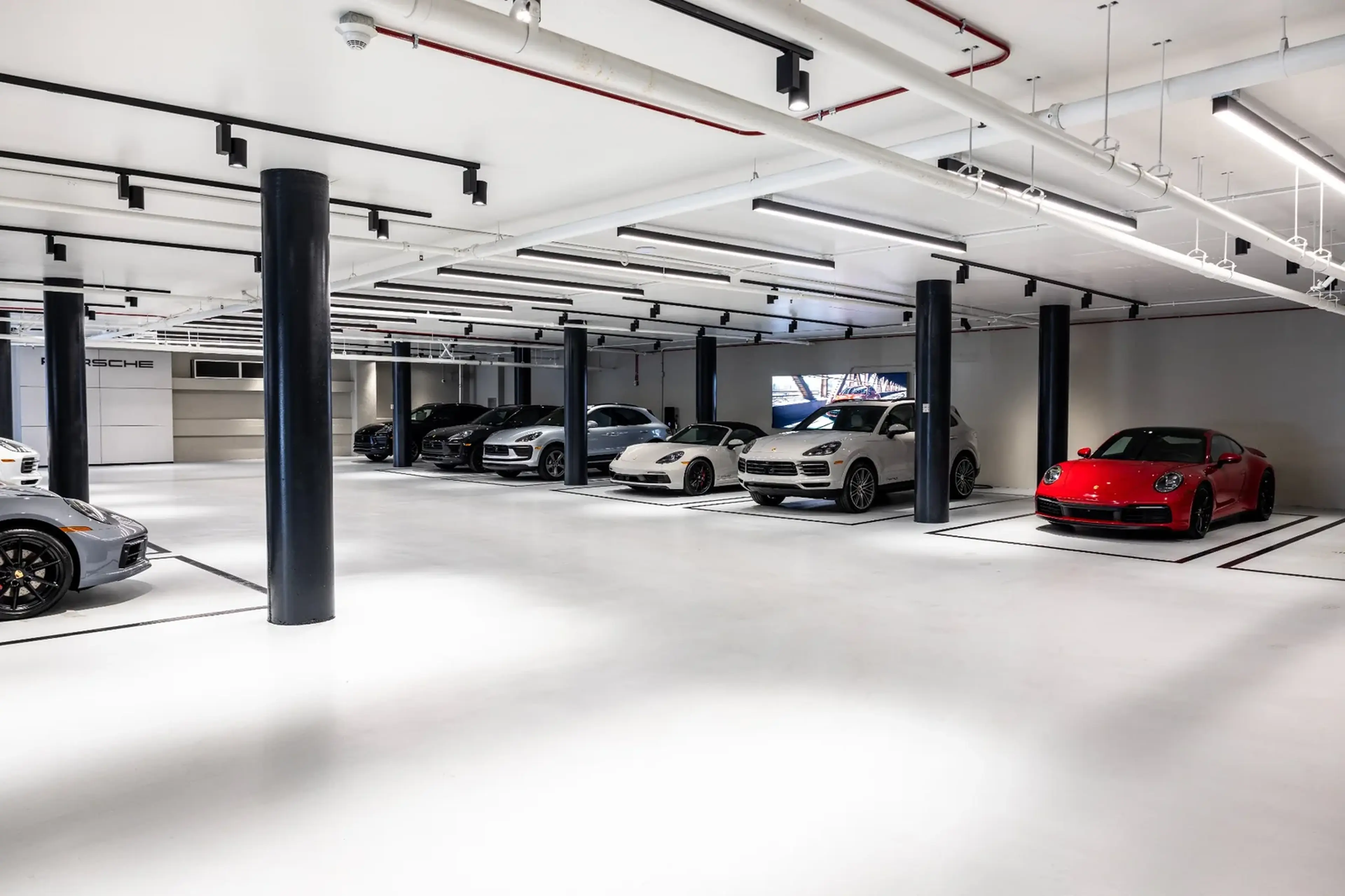 A modern, spacious showroom with a row of luxury cars parked, featuring sleek design and bright lighting.