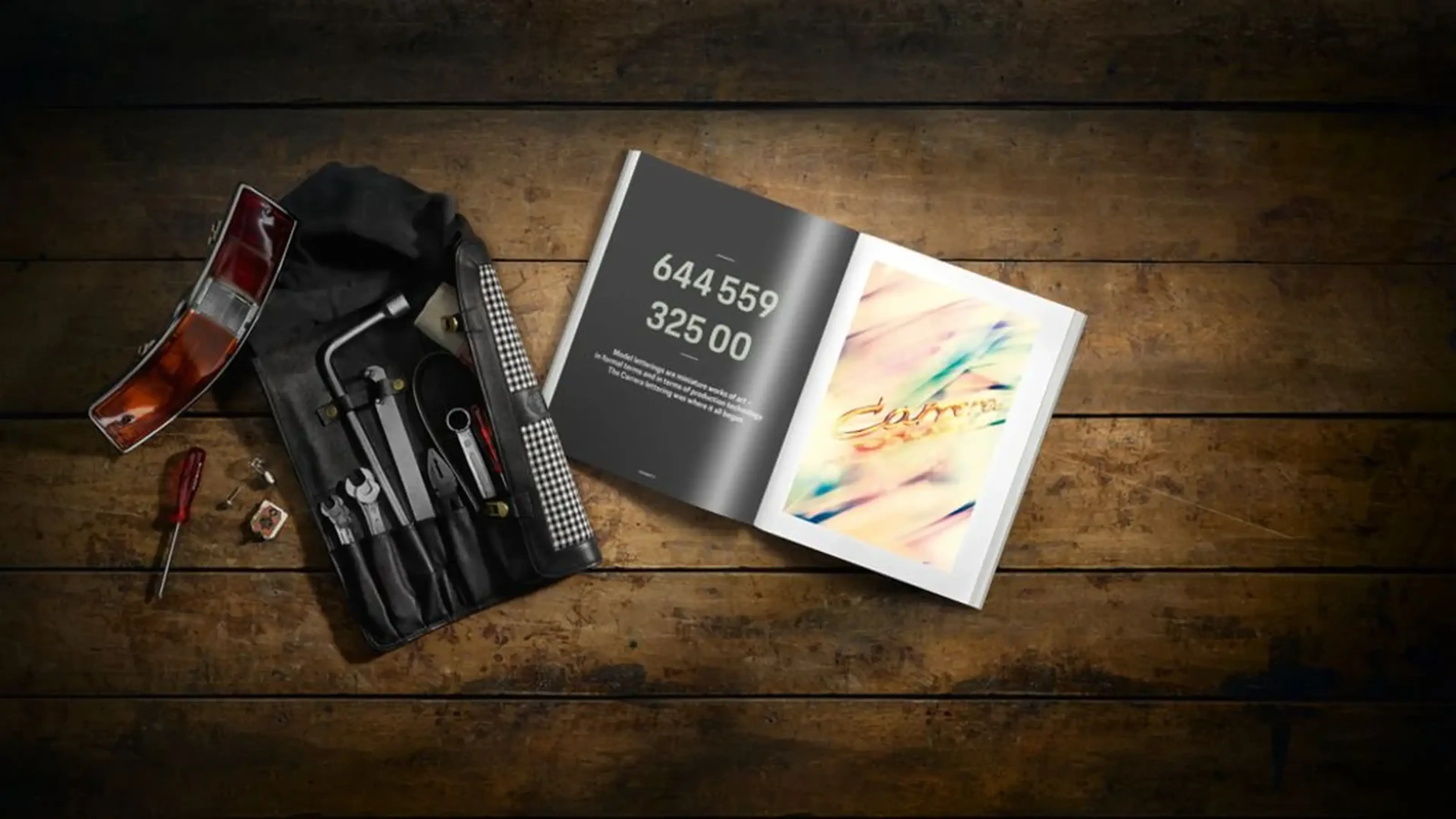An open book with numbers and colorful artwork on a wooden table next to tools, a taillight, and a screwdriver.