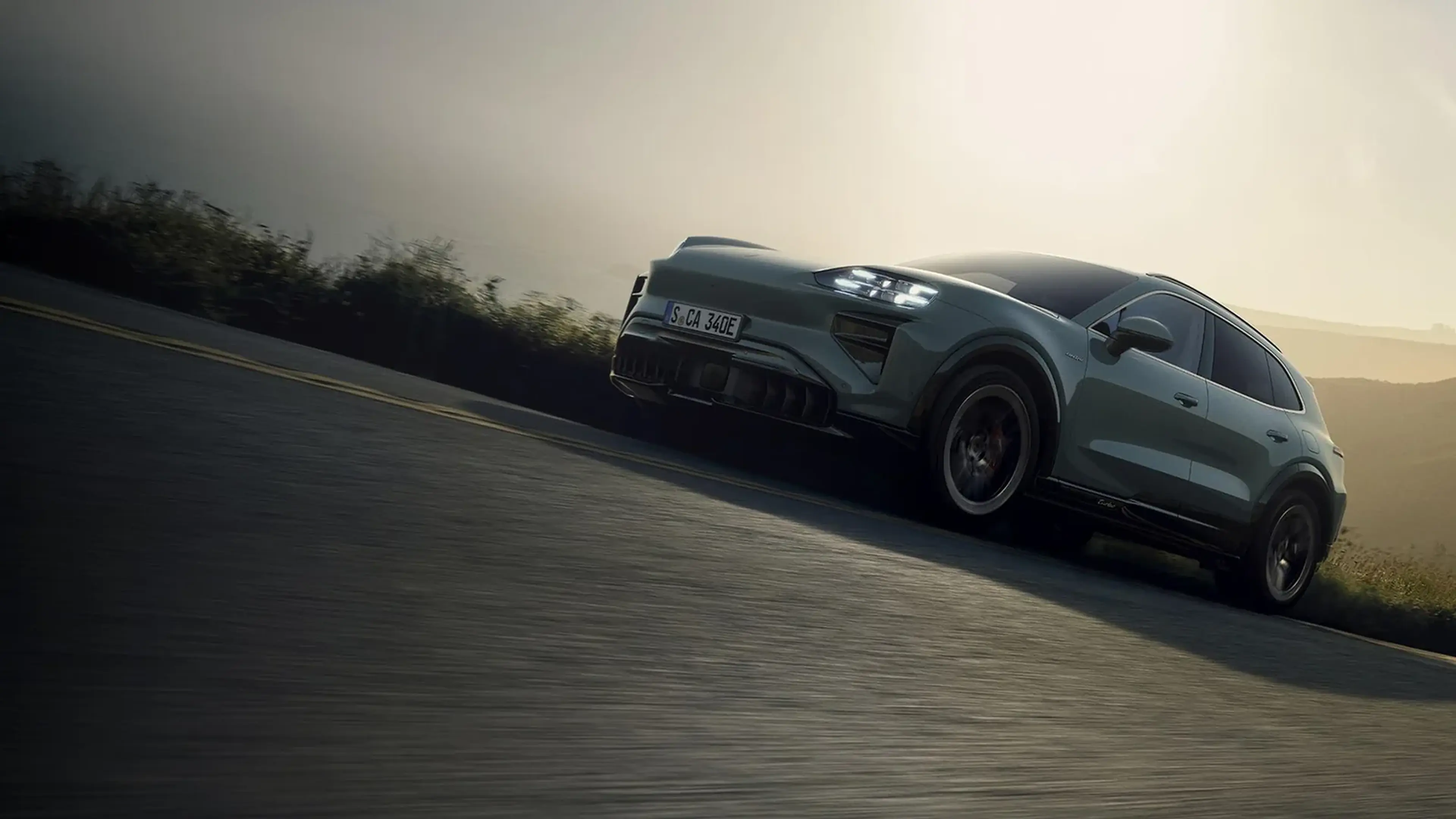 Porsche SUV driving along a hillside road