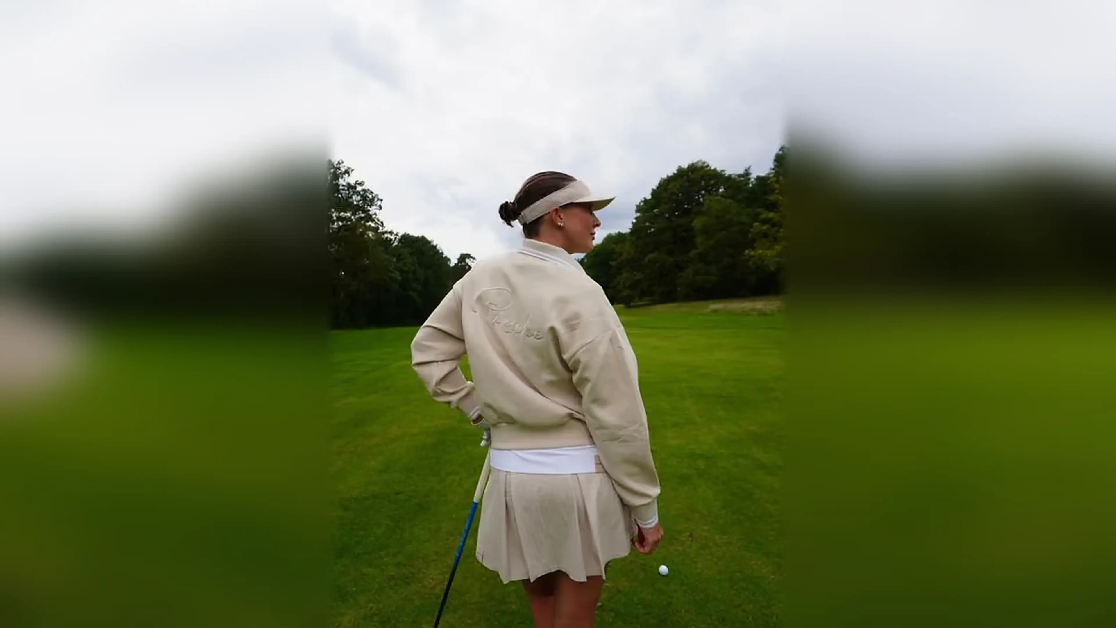 Woman wearing Porsche golf apparel on a golf course.