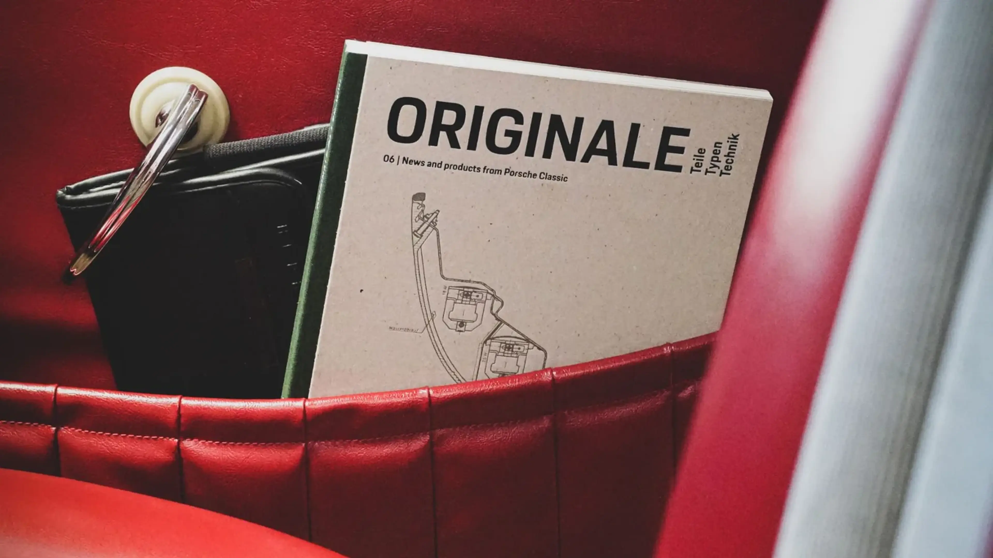 A beige magazine titled "ORIGINALE" with a technical drawing is tucked inside a red leather pocket.