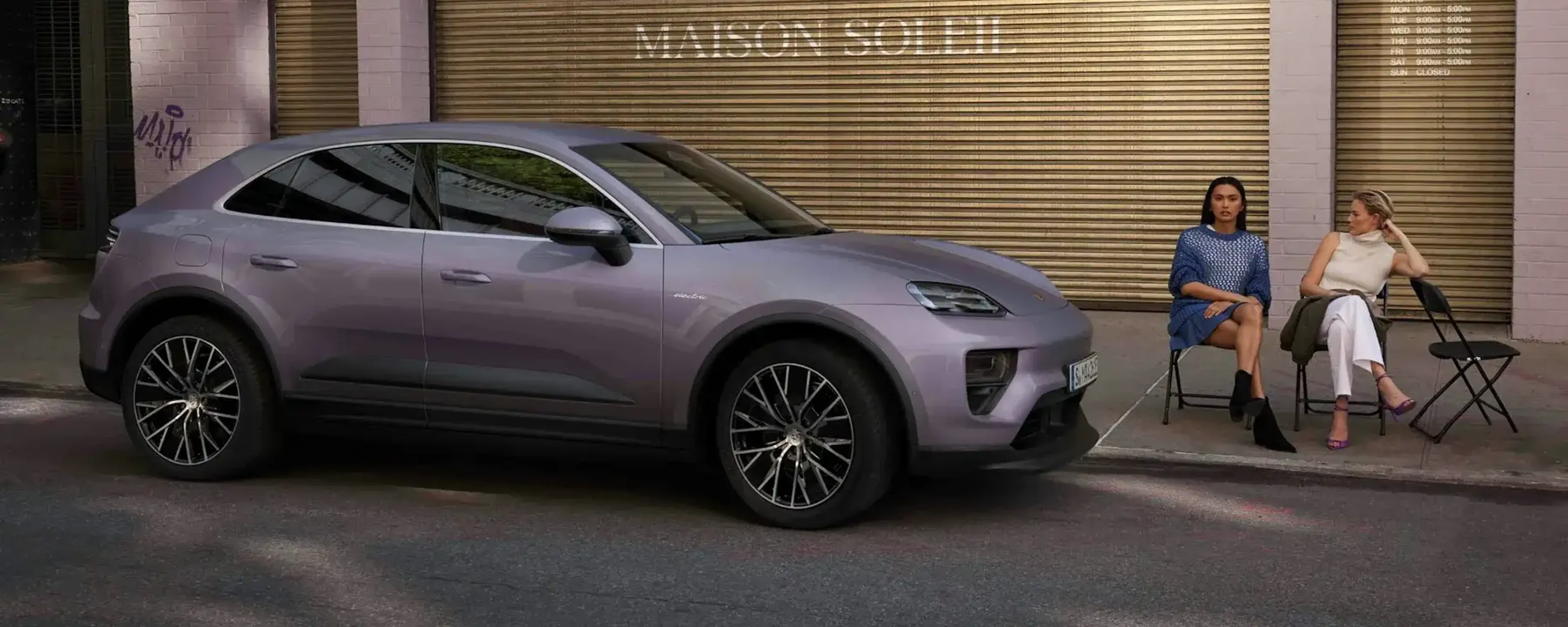 two women sitting next to a New Macan Electric