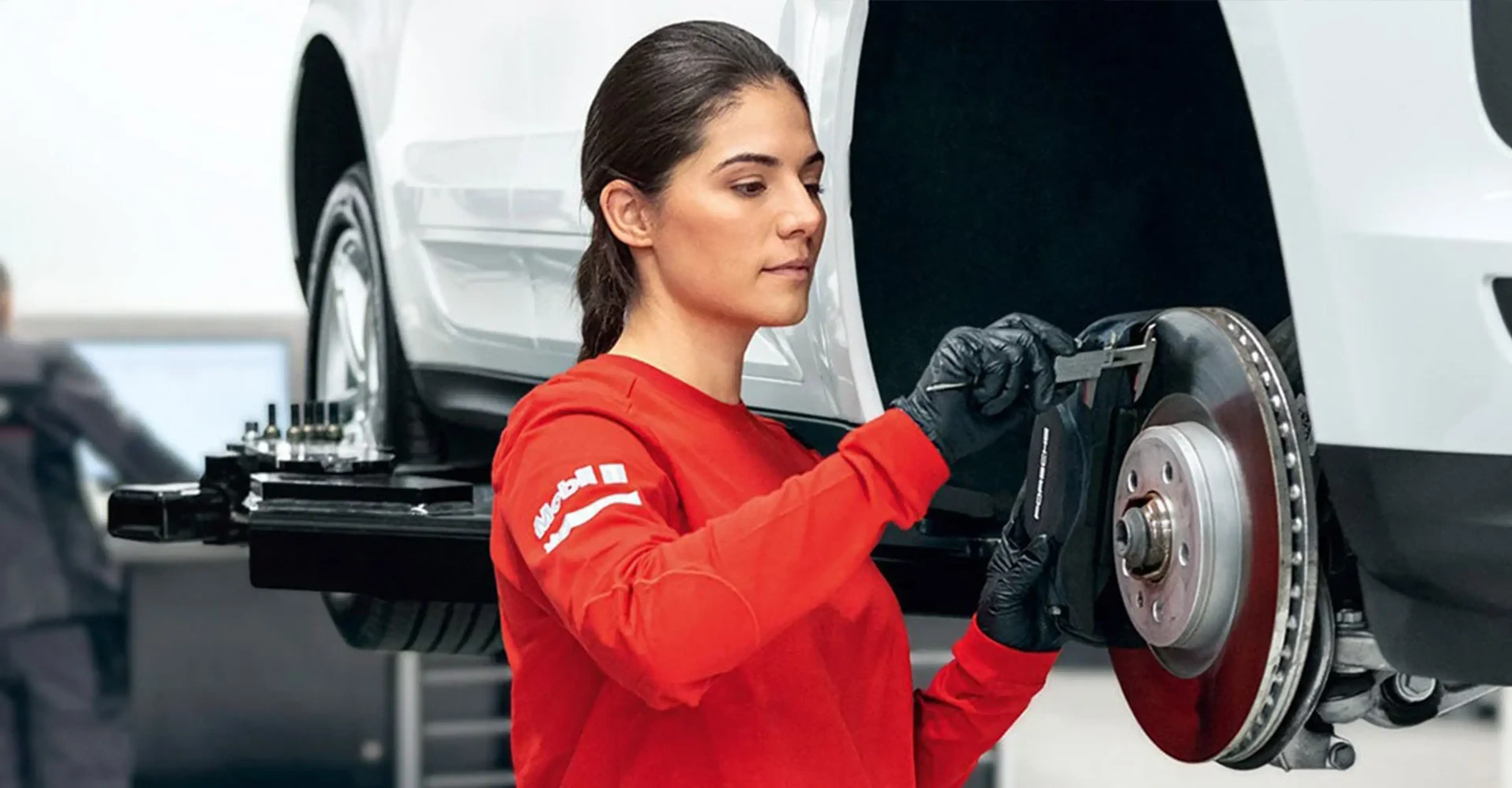Porsche technician in a red uniform holding a wheel