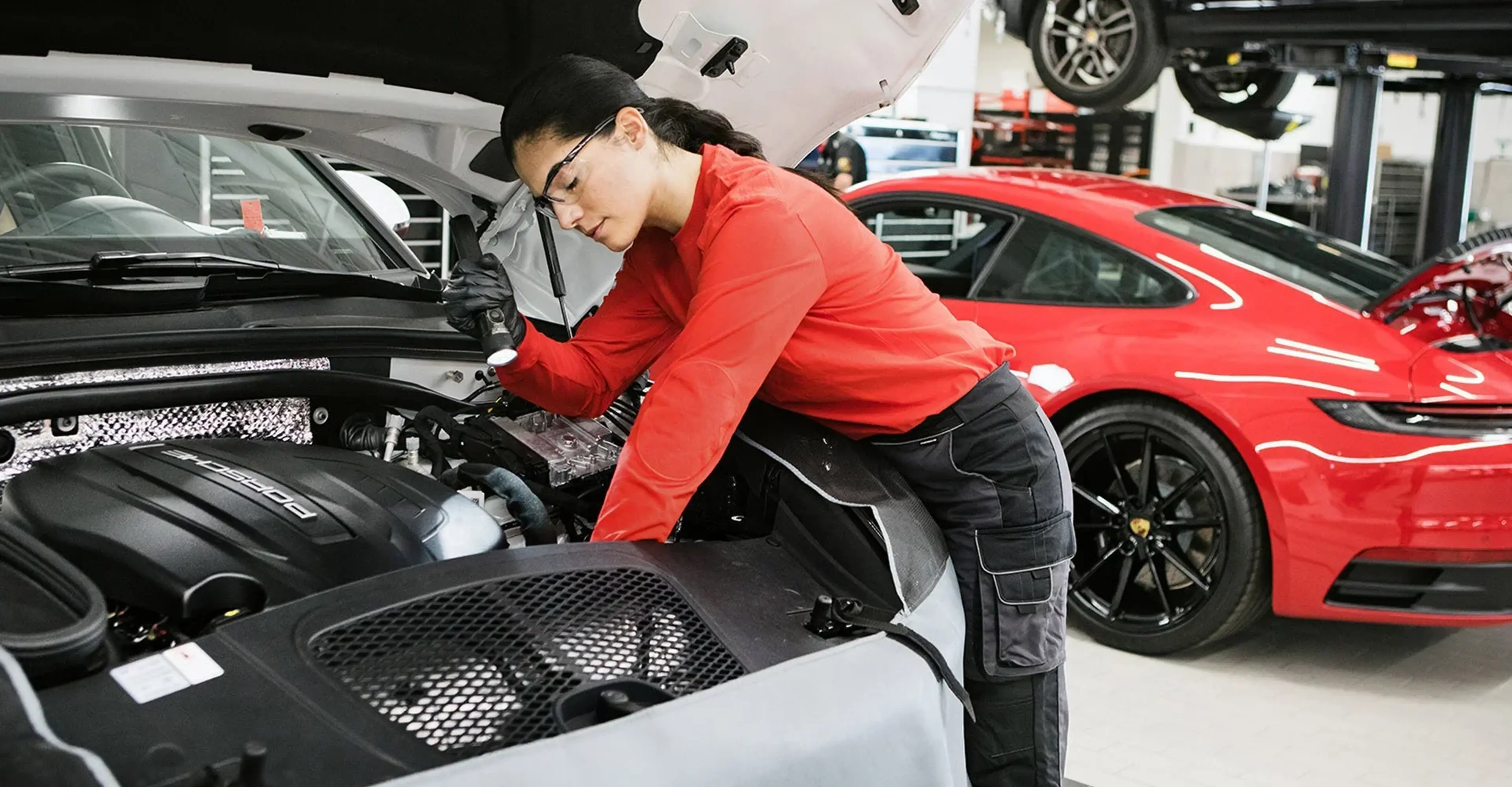 Technician working under the hood of a red Porsche