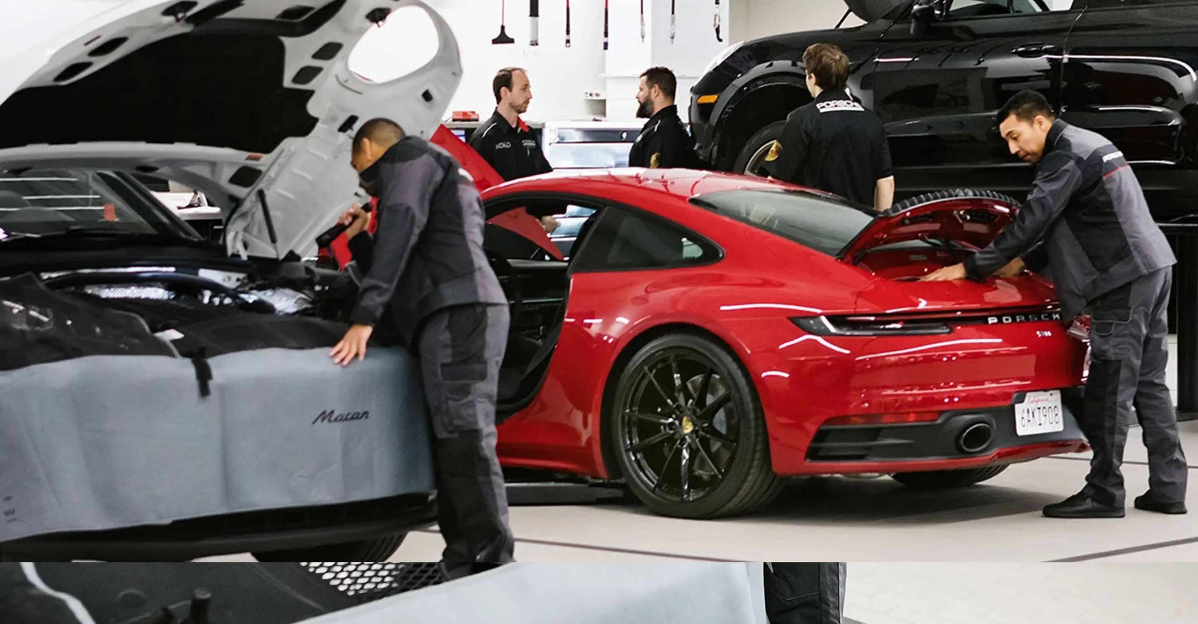 Porsche service advisors with a red 911 in the service drive