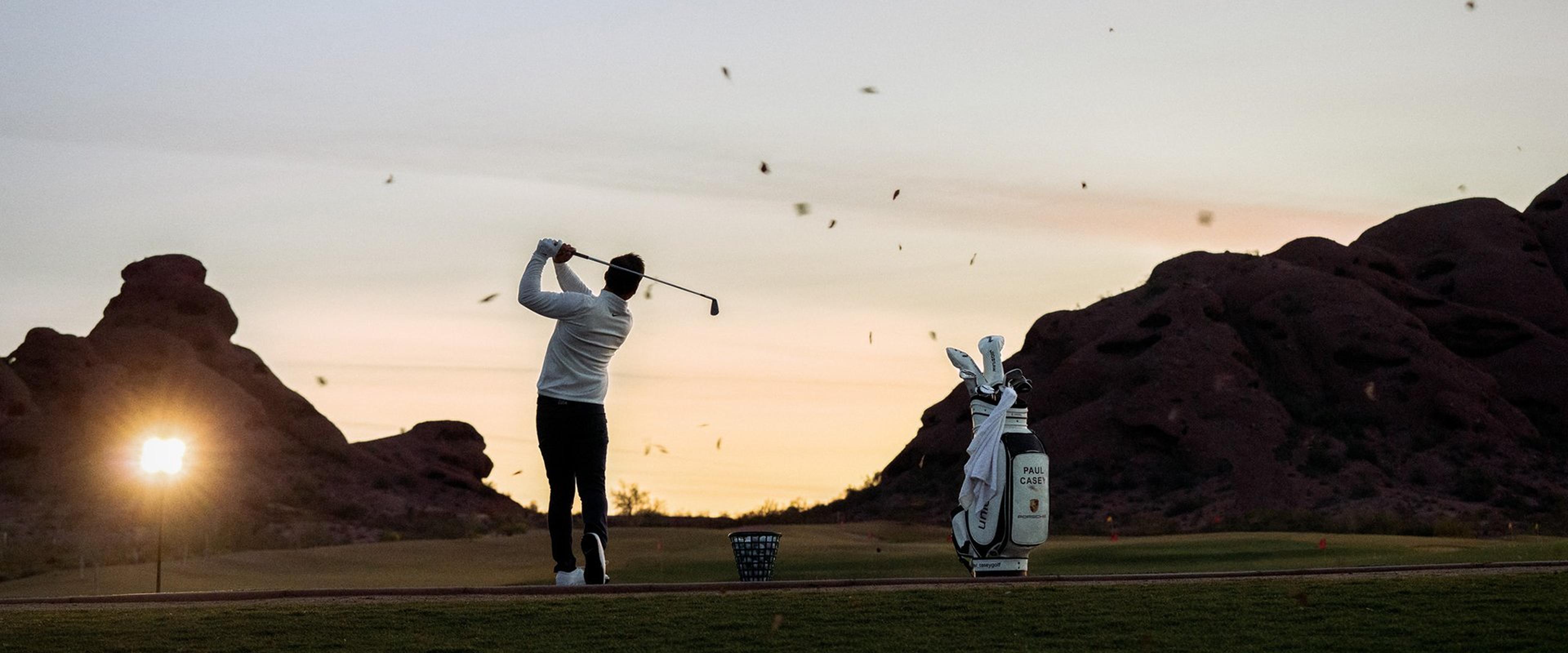 Ein Golfspieler schlägt in der Abenddämmerung einen Golfball weit in die Ferne.