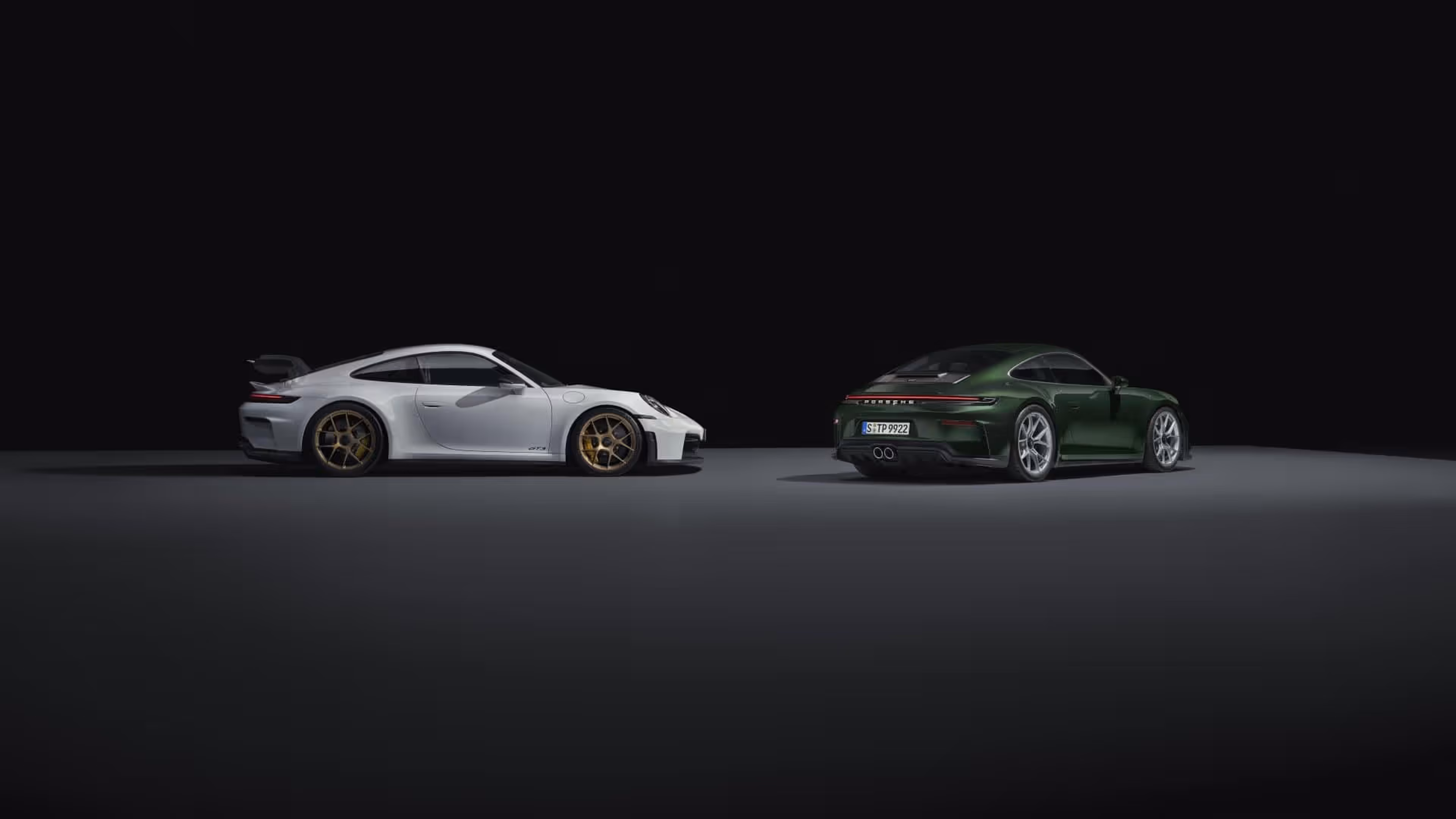 Two Porsche 911 GT3 next to each other in a dark environment.