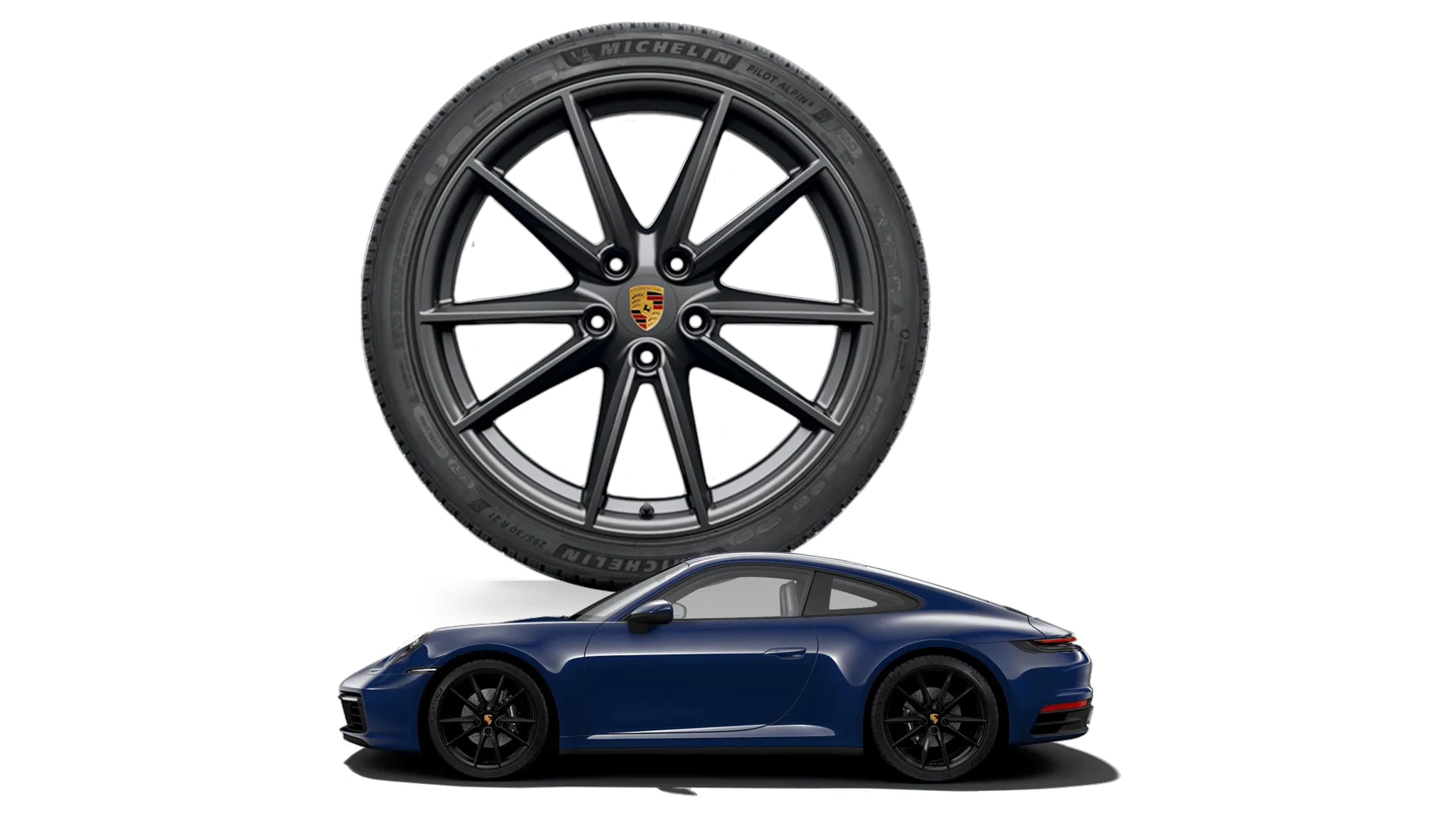 A blue sports car with a badge on the rear fender, parked next to a large black alloy wheel with a colorful emblem at the center.