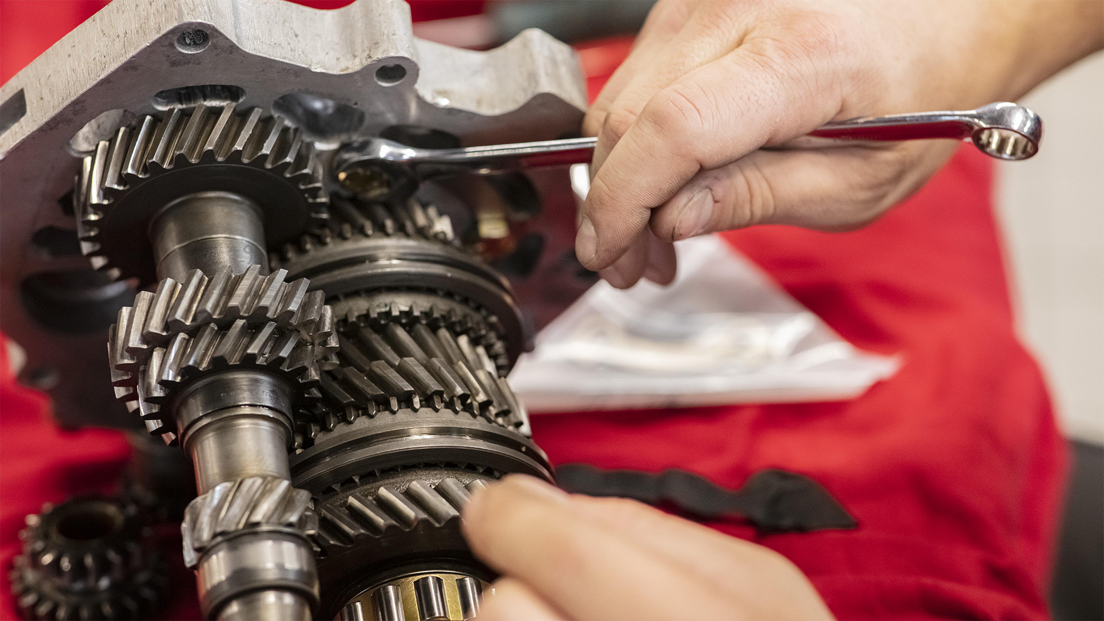 Classics Gear g50 - Hands using a wrench to assemble or adjust a complex set of gears, likely part of a mechanical system or engine.