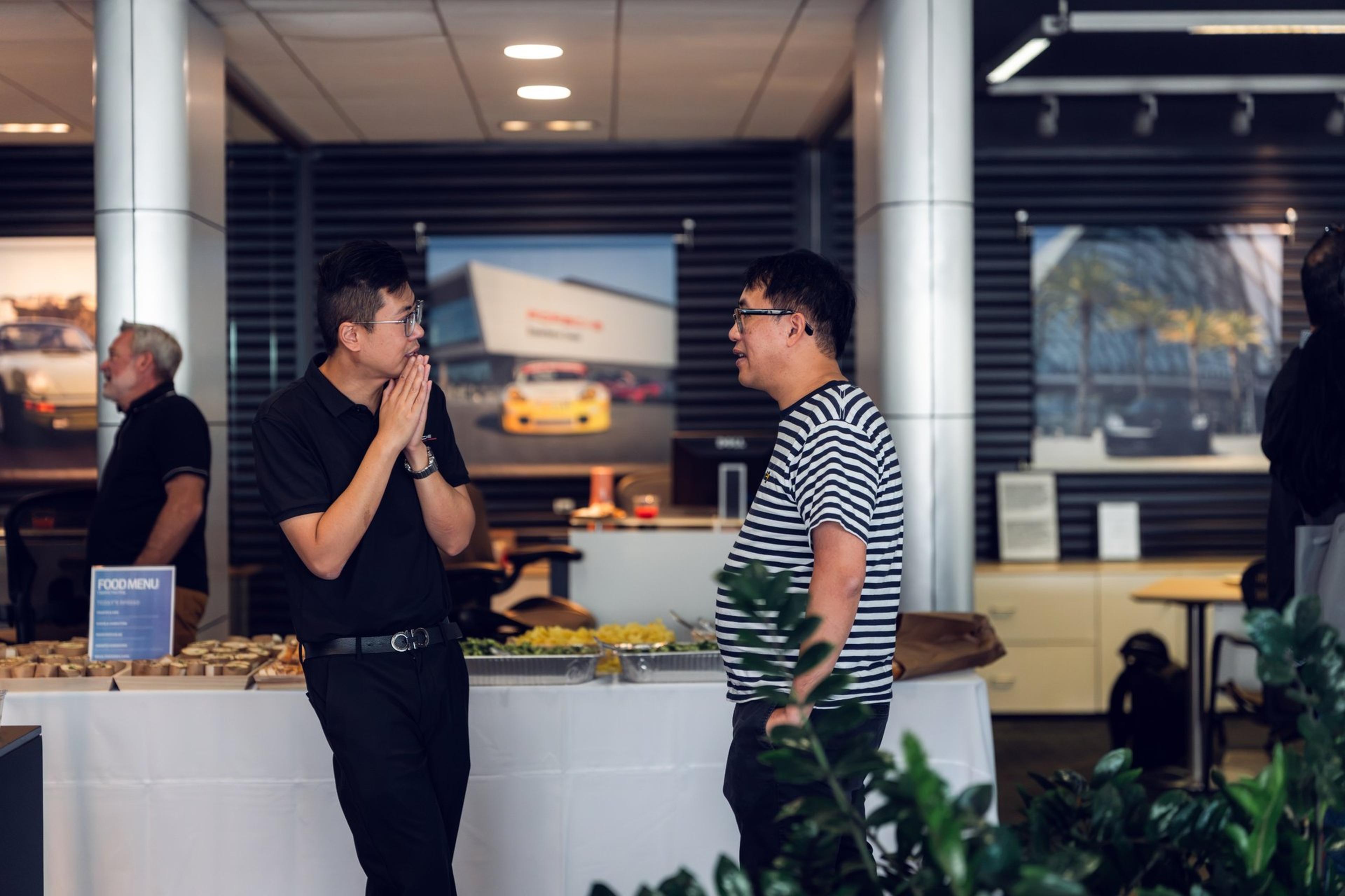 Guests chat by the catered table during the Cayenne Electric unveiling event at McKenna Porsche