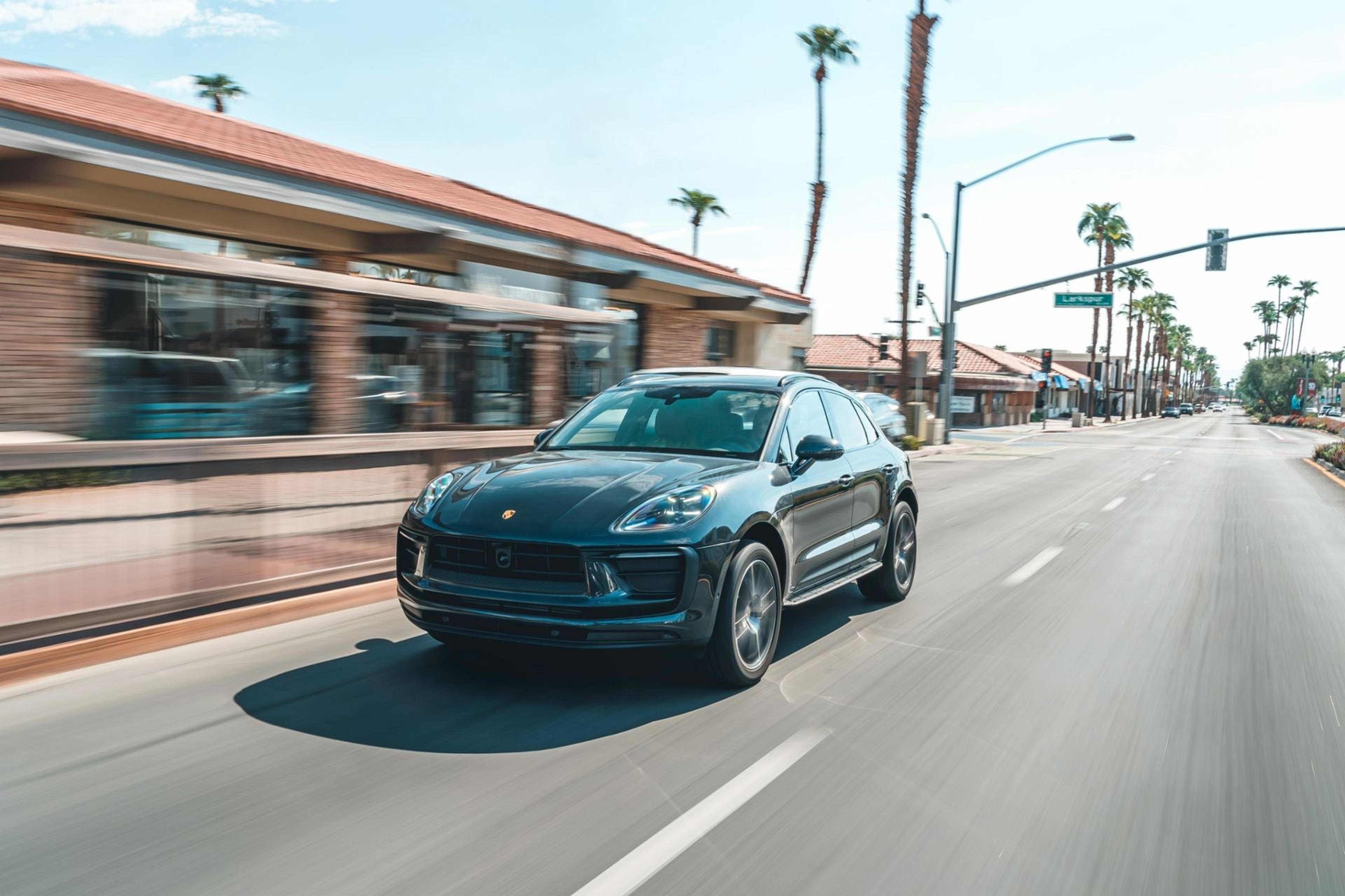 Volcano Grey Porsche Macan driving through a palm-lined town