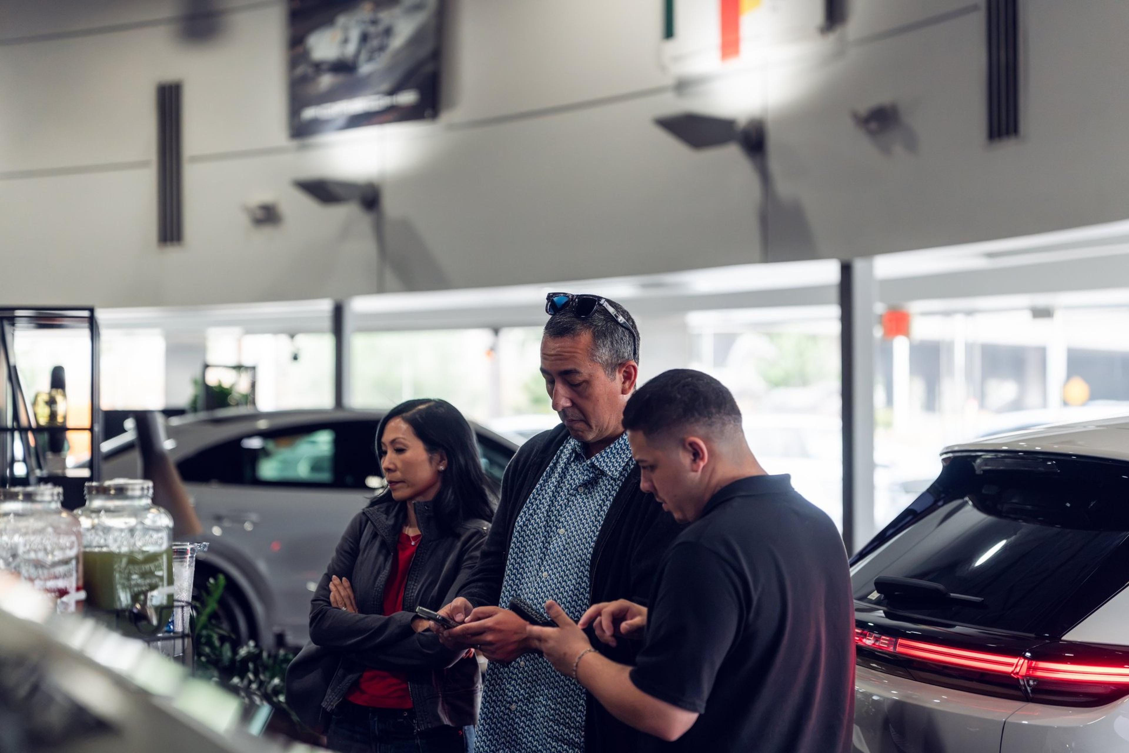 Guests review Cayenne Electric details on their phones in the McKenna Porsche showroom