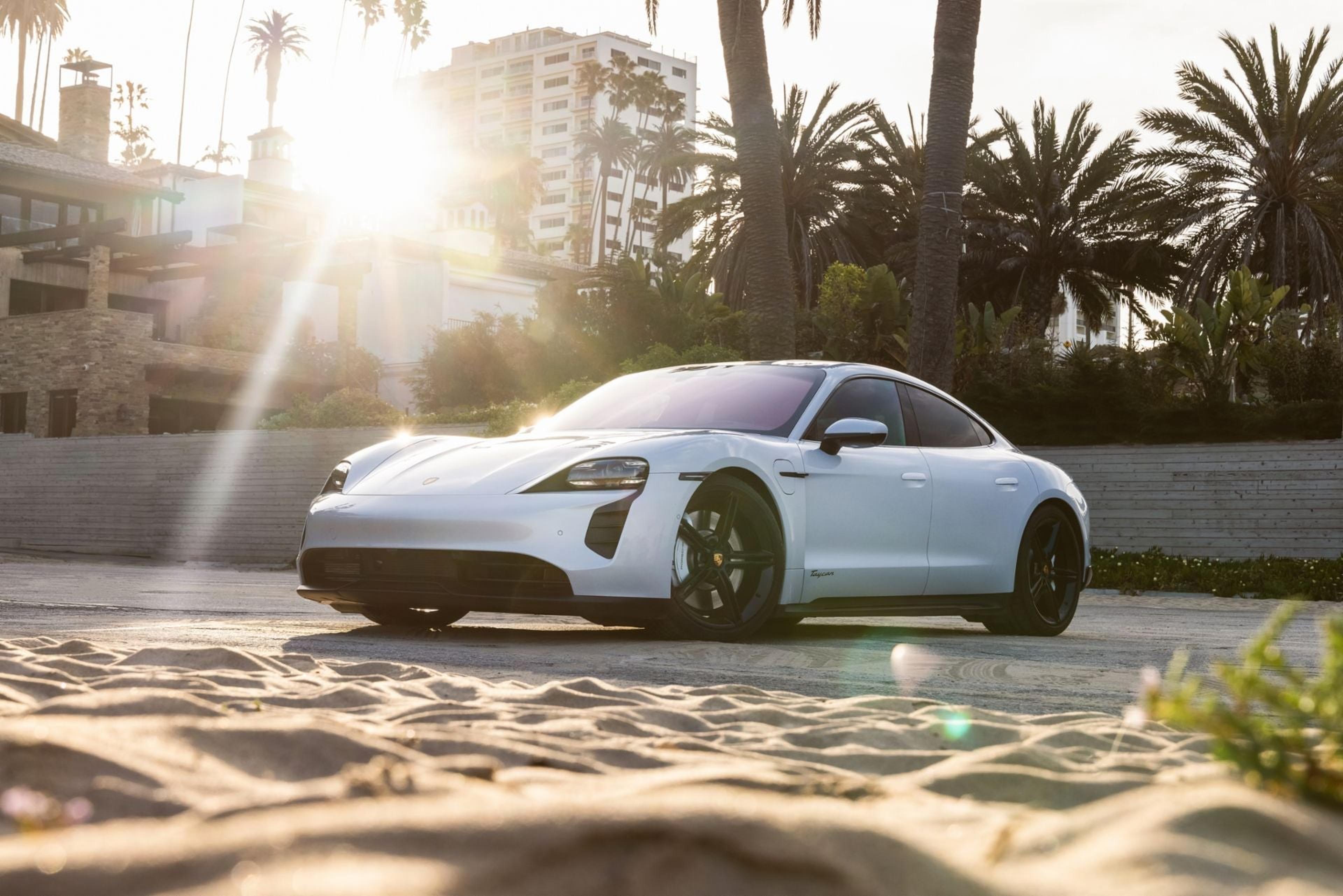 White Porsche Taycan parked on a sandy beach